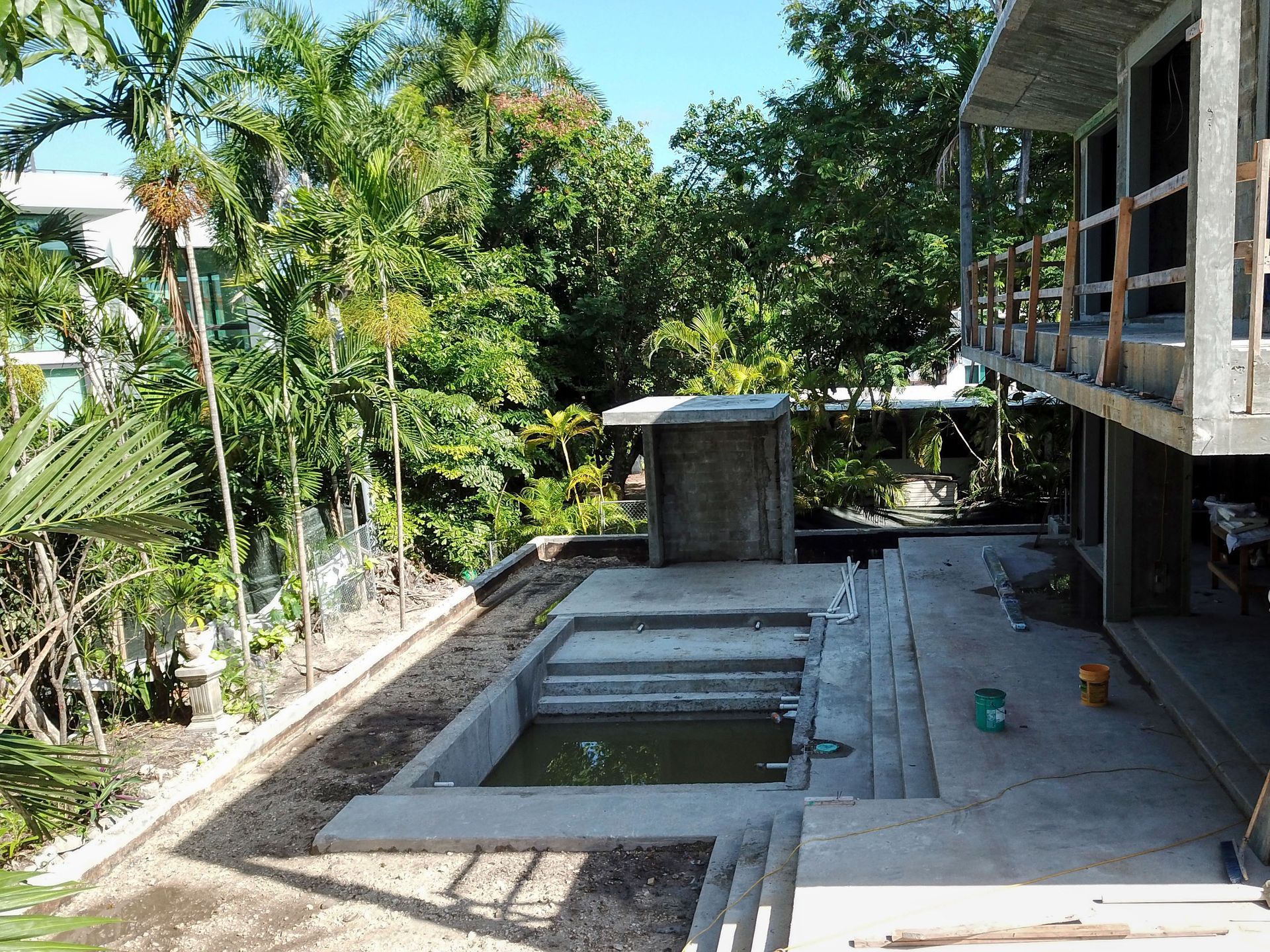 A swimming pool is under construction in the backyard of a house