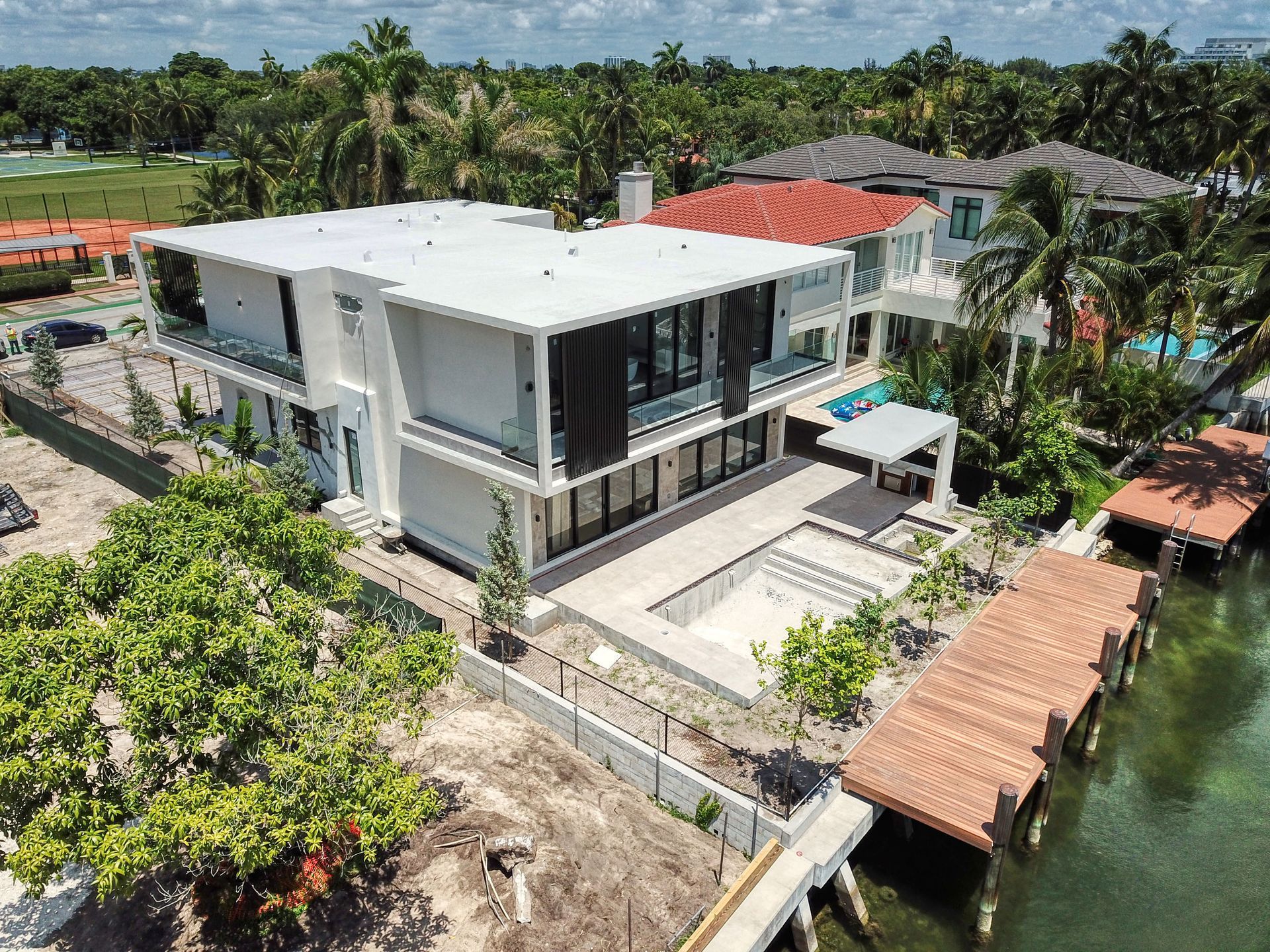 Modern waterfront home with a pool and dock surrounded by lush greenery.