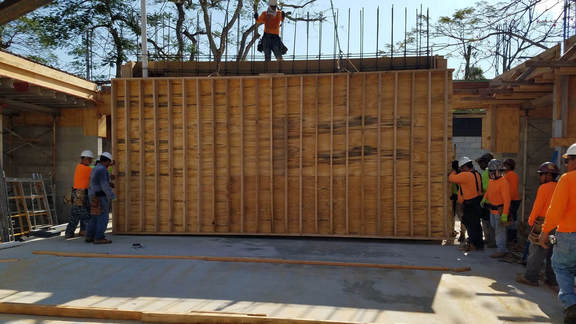 A group of construction workers are working on a large wooden wall