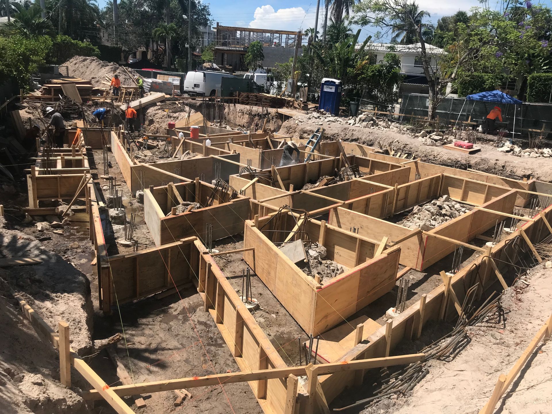 Wooden forms for a building foundation under construction outdoors. Workers are present.