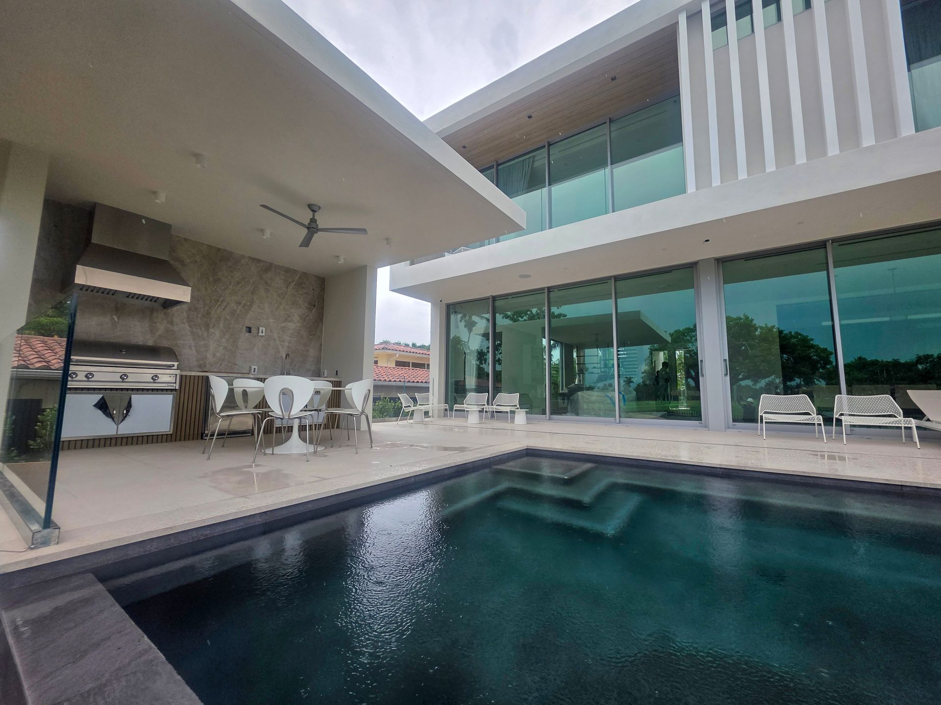 Modern house with pool, outdoor kitchen, and large windows.
