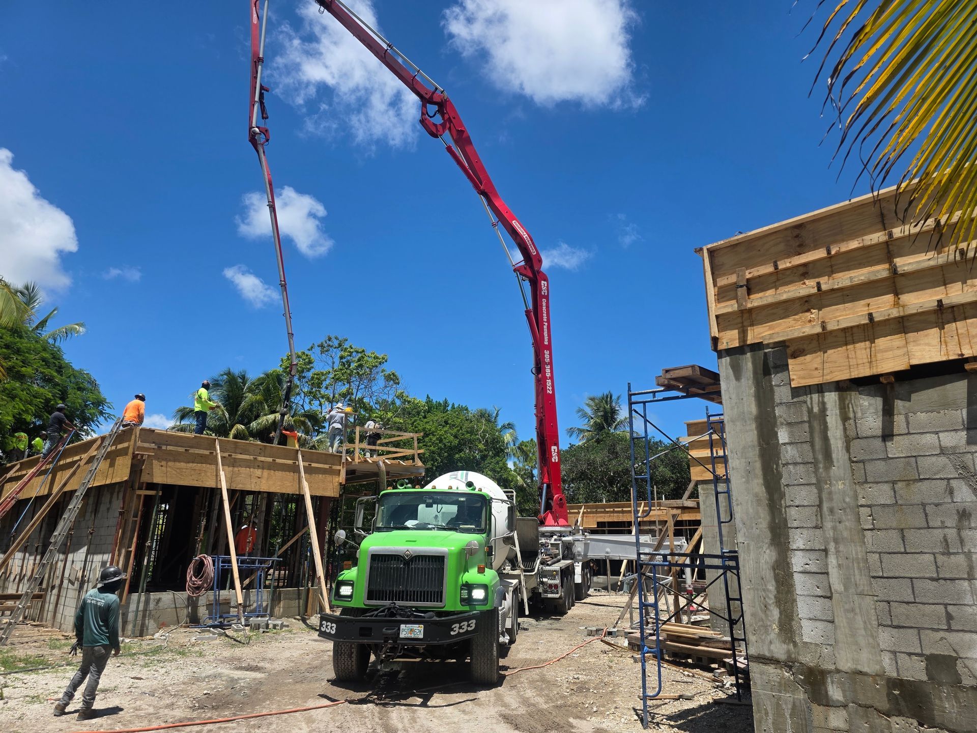 Concrete truck pouring cement at a construction site with workers under a bright blue sky.