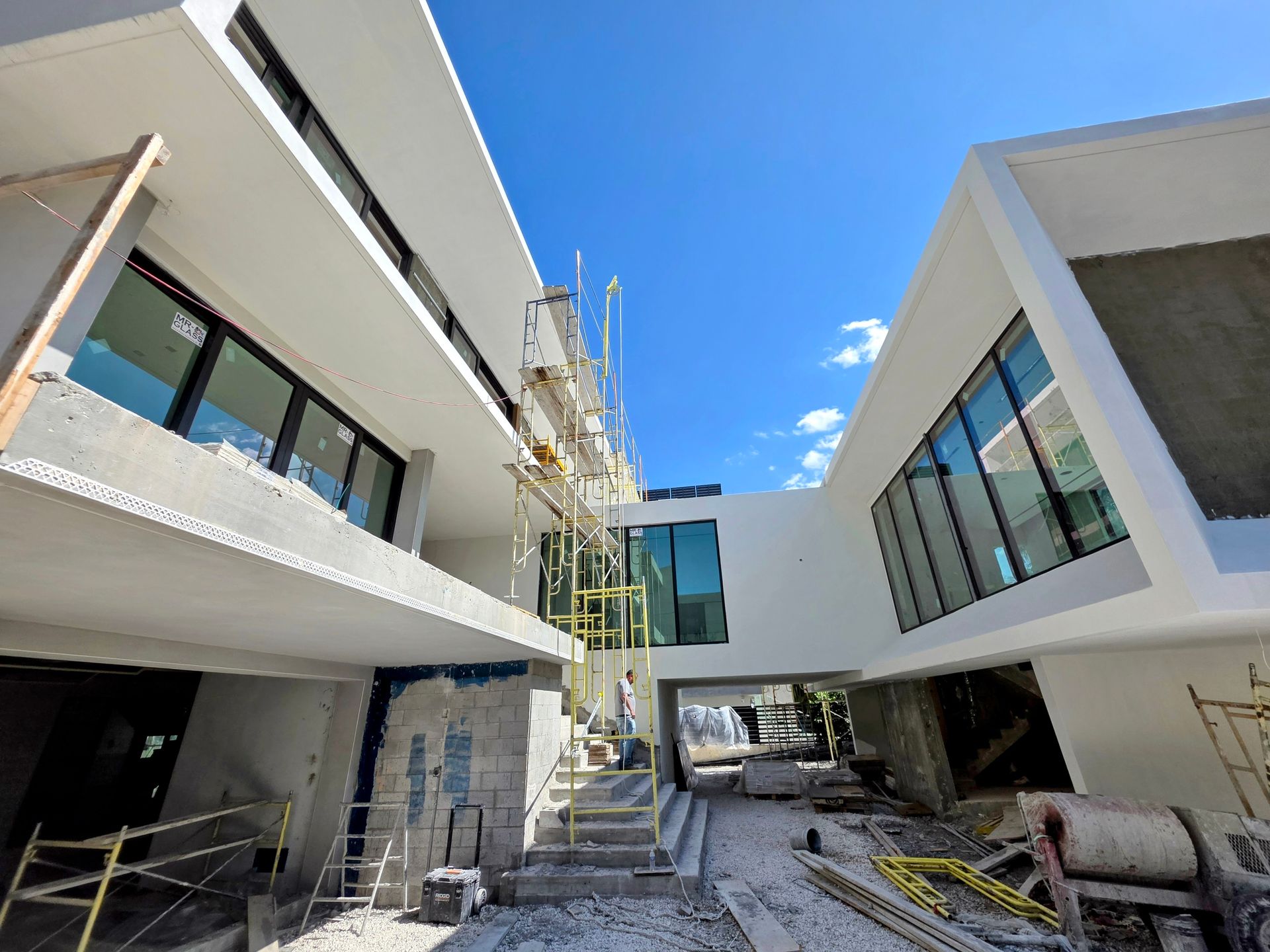 Modern multi-story building under construction with scaffolding against a blue sky.