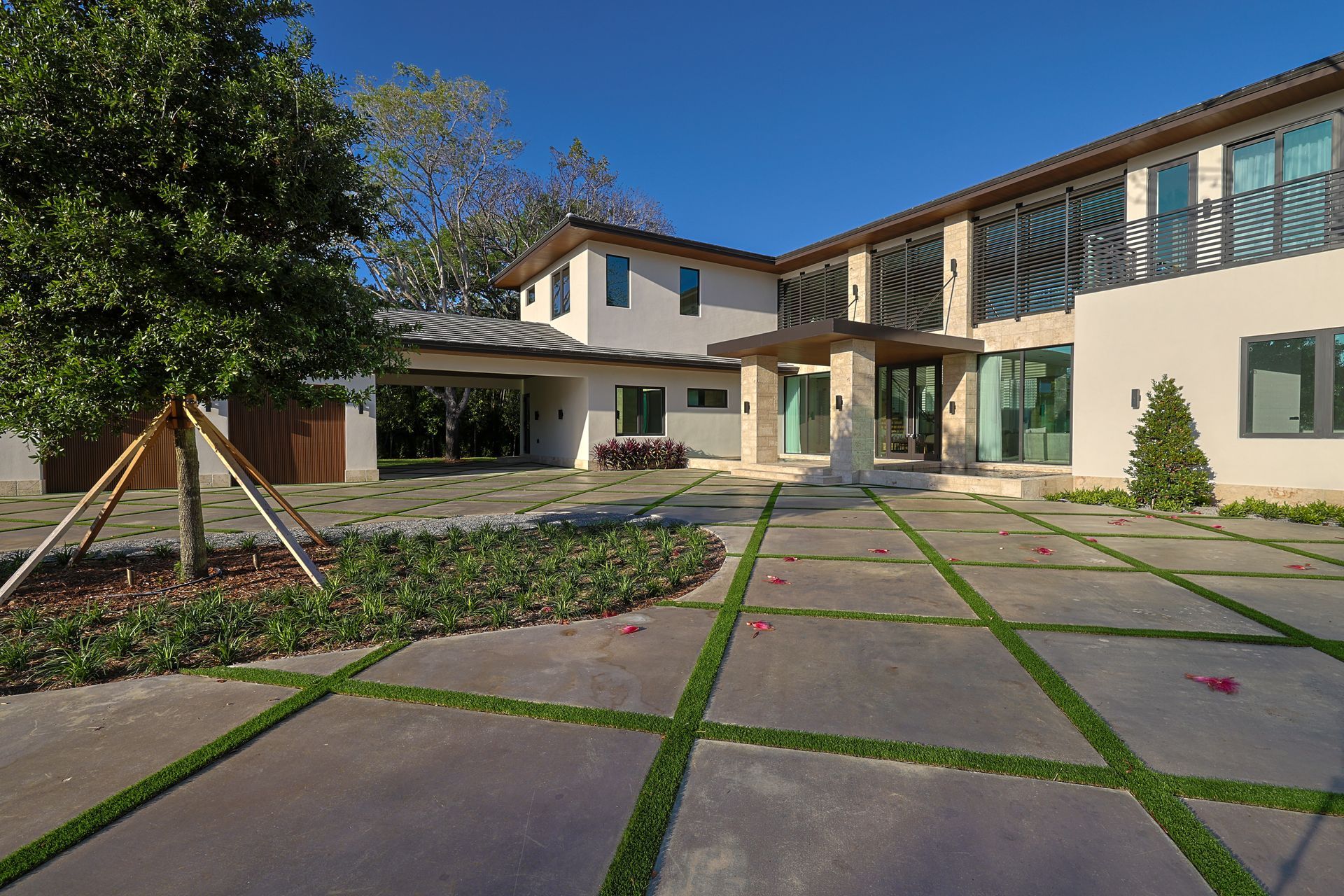 Modern two-story house with a stone and grass paved driveway and lush landscaping.