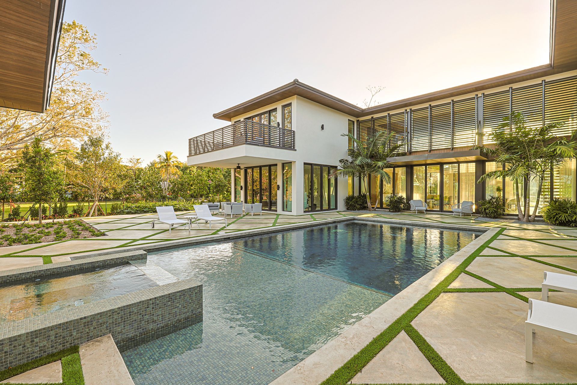 Luxury home with a pool, patio, and lush landscaping on a sunny day.