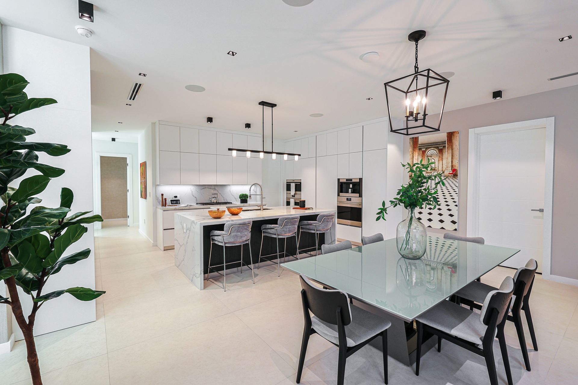 Modern kitchen and dining area with white cabinets, dark island, and glass table.