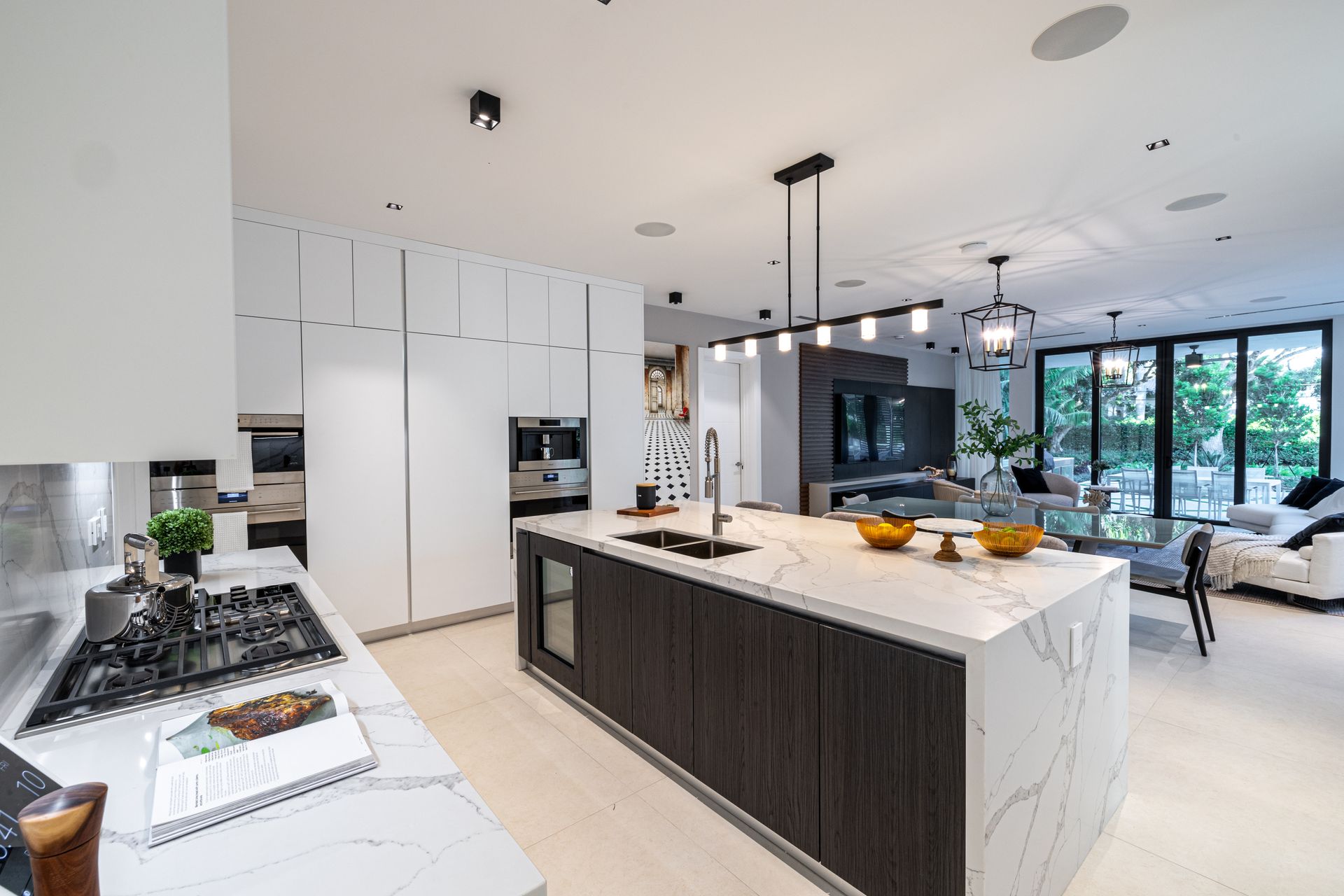Modern kitchen with island, white countertops, dark cabinetry, and integrated appliances.