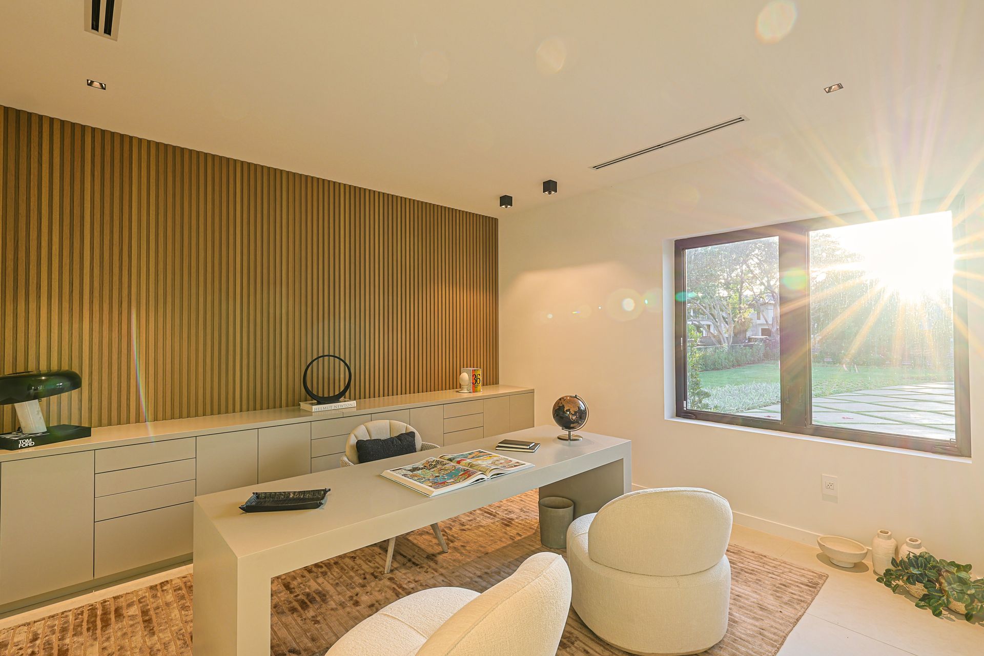 Modern office with desk, cabinets, and window letting in bright sunlight.