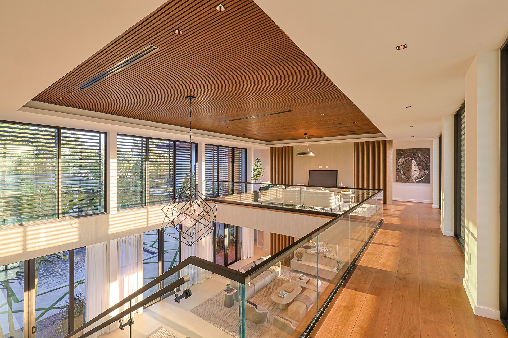 Interior view of a modern two-story home with wood ceilings, glass railings, and large windows.