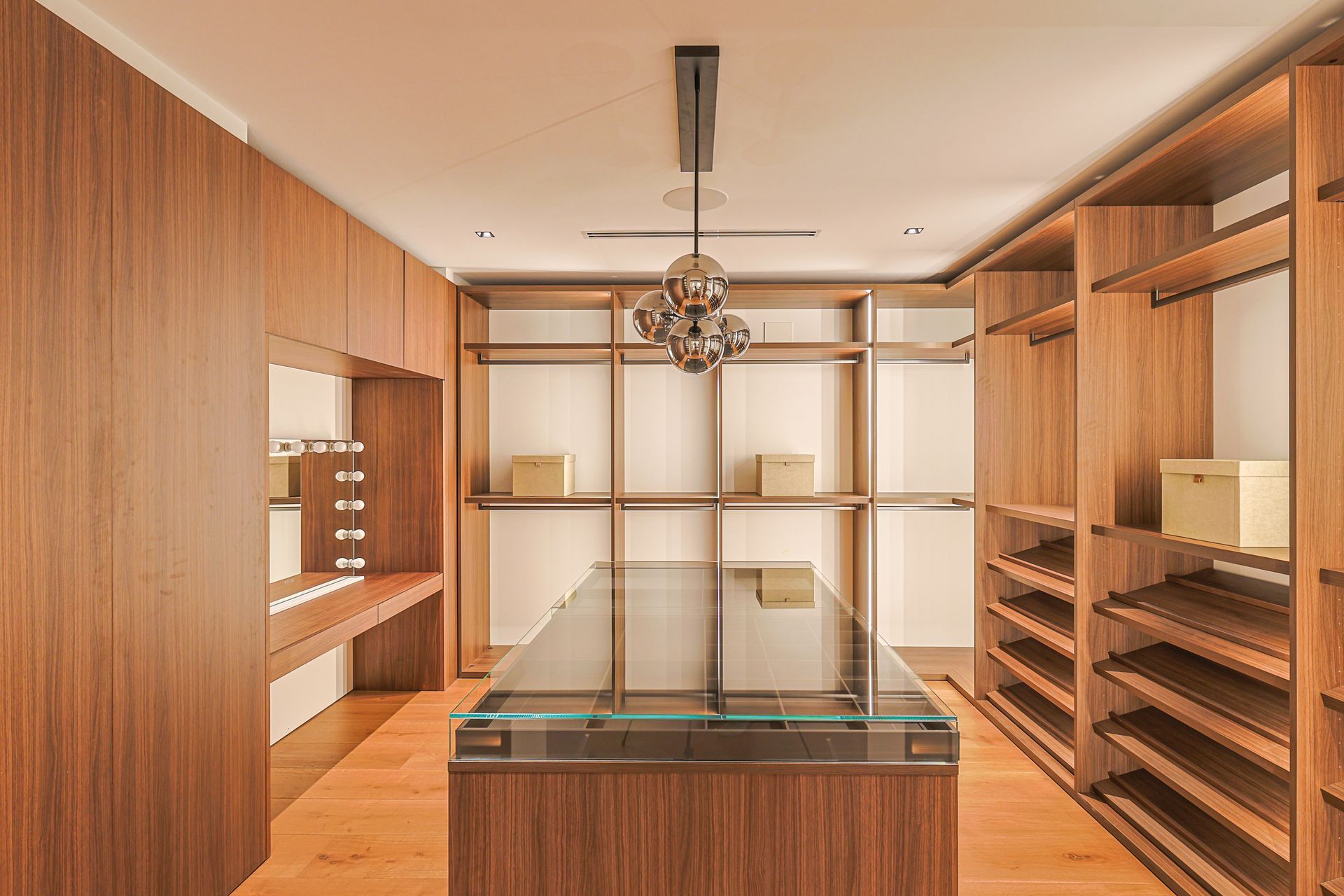 Walk-in closet with wooden shelves, cabinets, and a central display case.