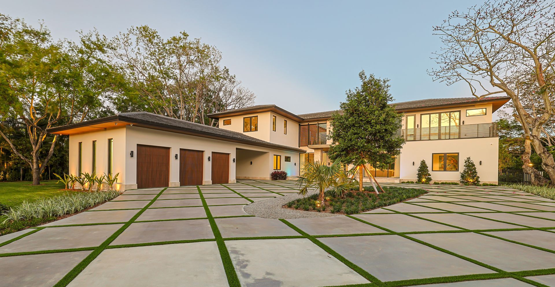 Modern white house with a paved driveway and green spaces.
