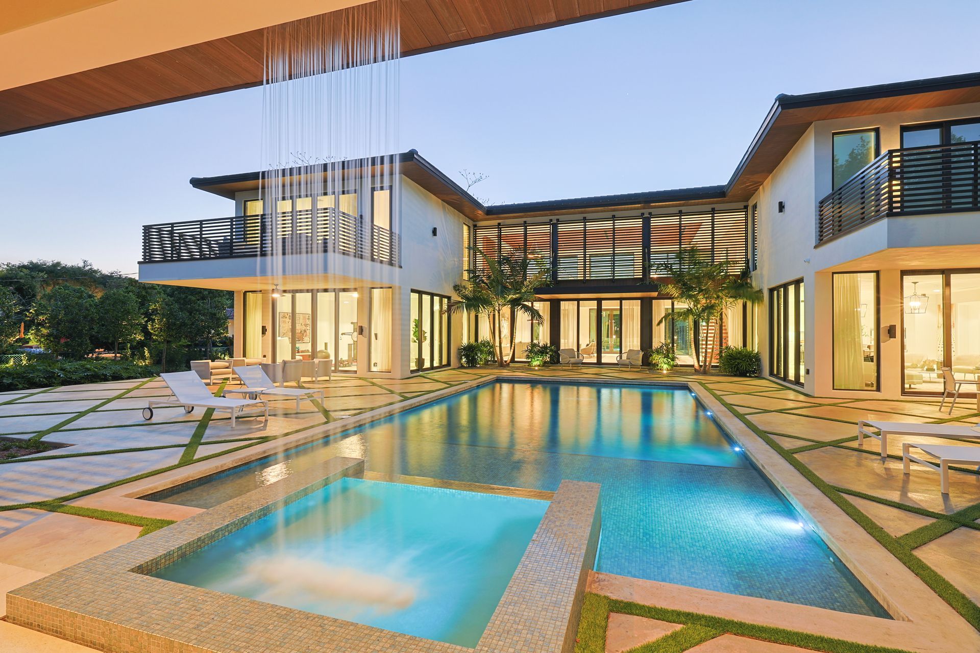 Luxury home with pool, water feature, and evening lighting.