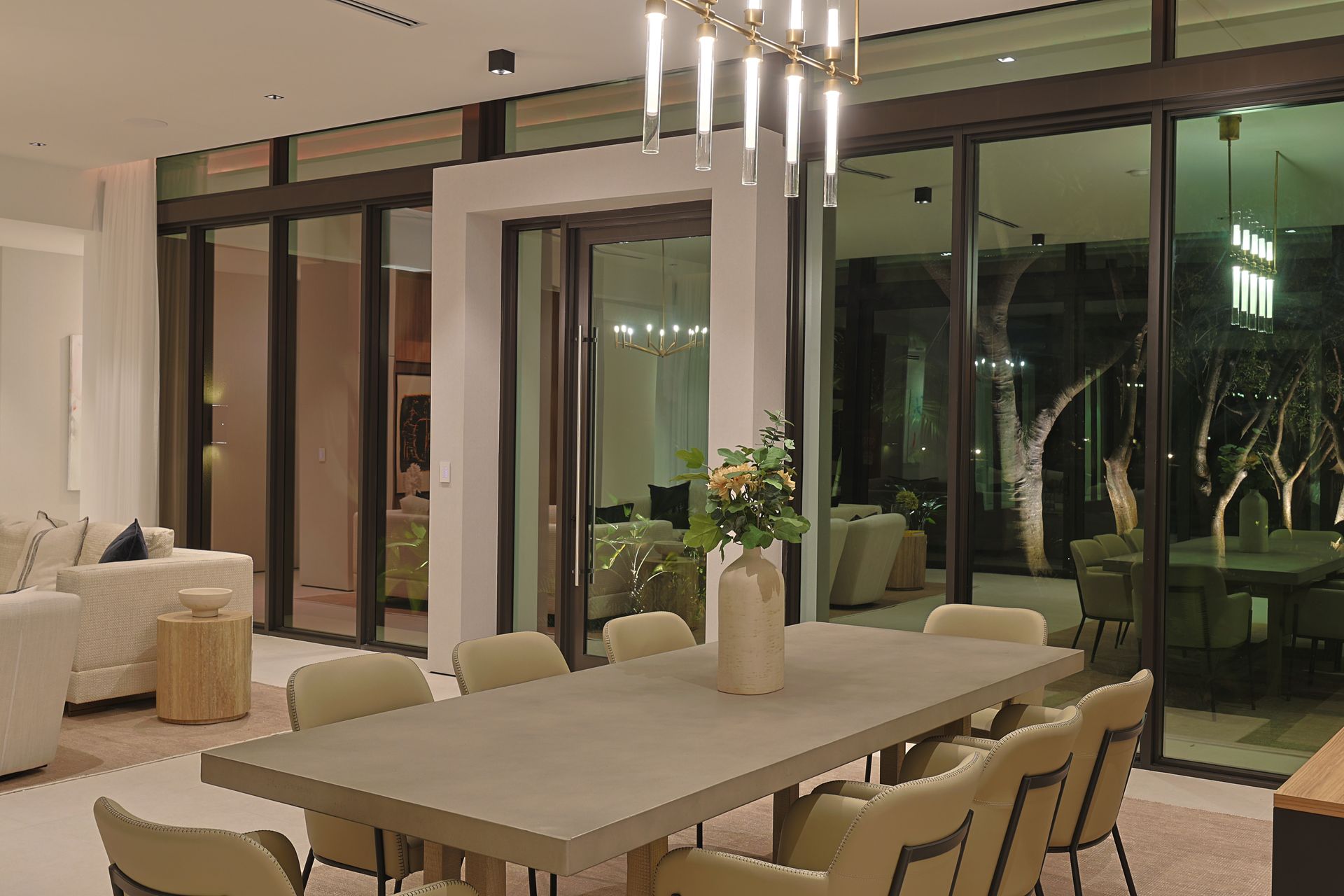 Modern dining room with a long concrete table, chairs, and large sliding glass doors.