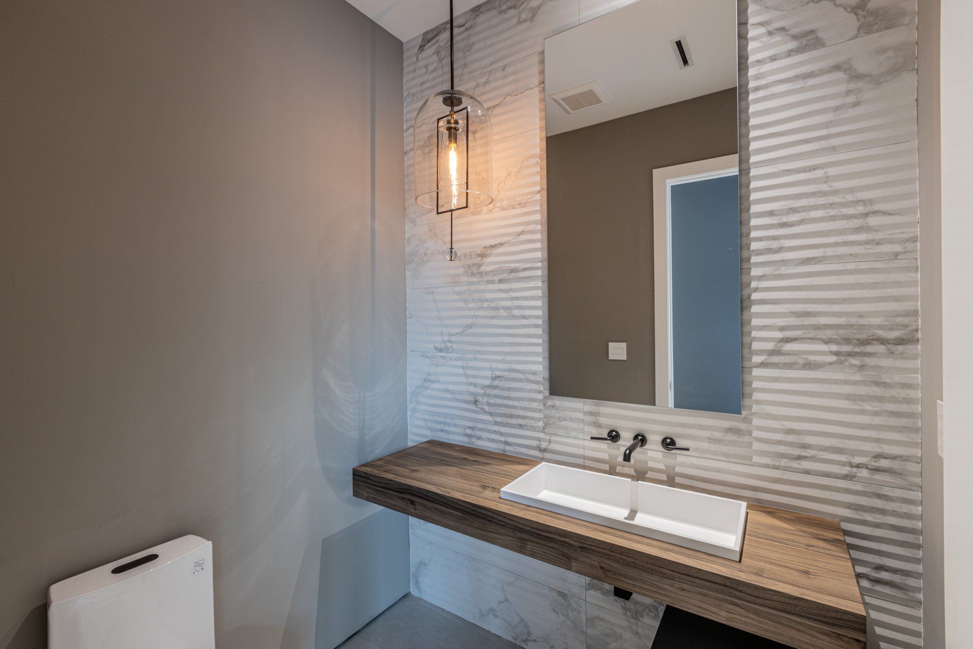 Modern bathroom with floating wooden vanity, white sink, and decorative wall tiles.