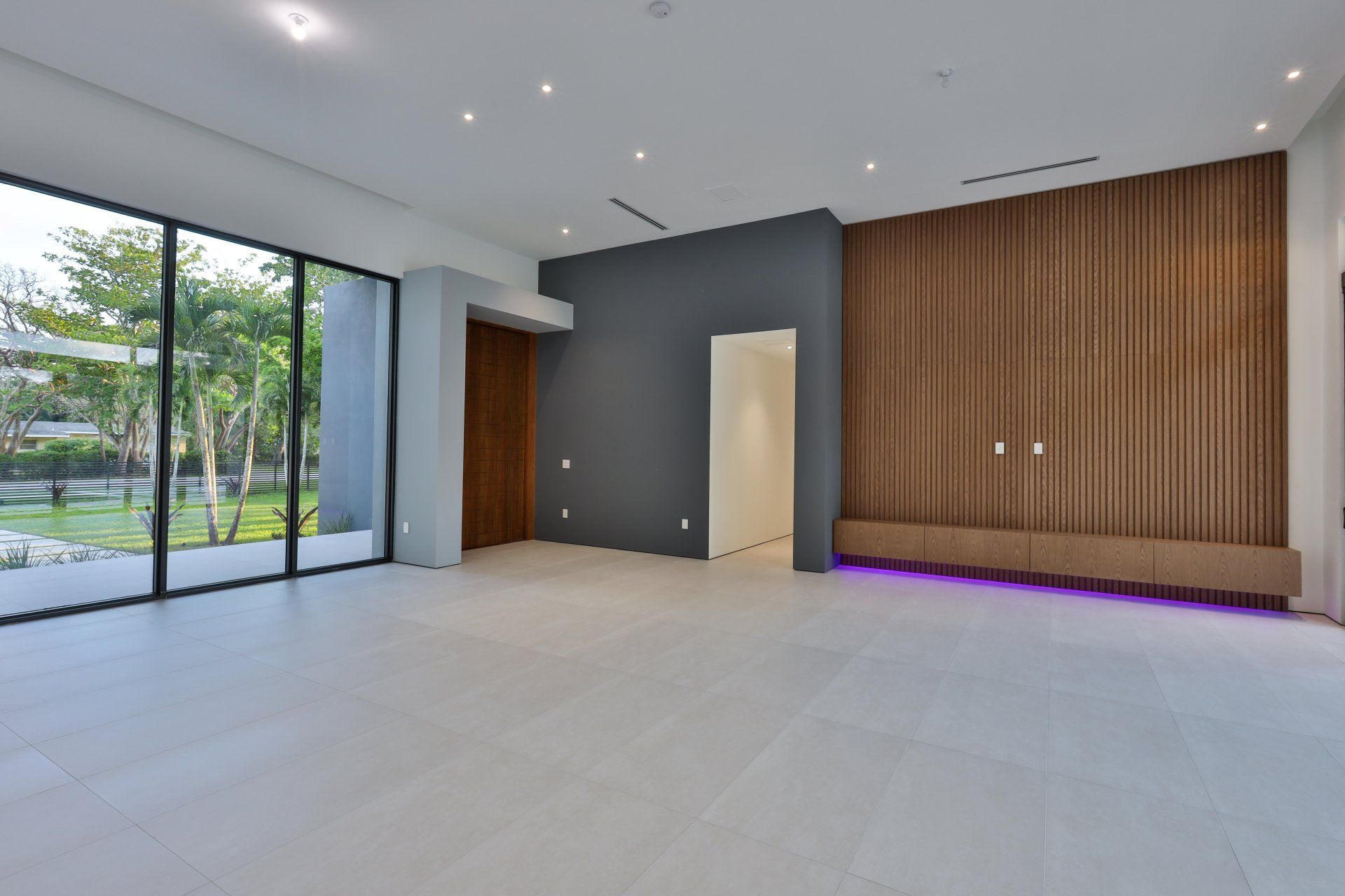 Empty modern room with large windows, wood panel wall, and gray accents.