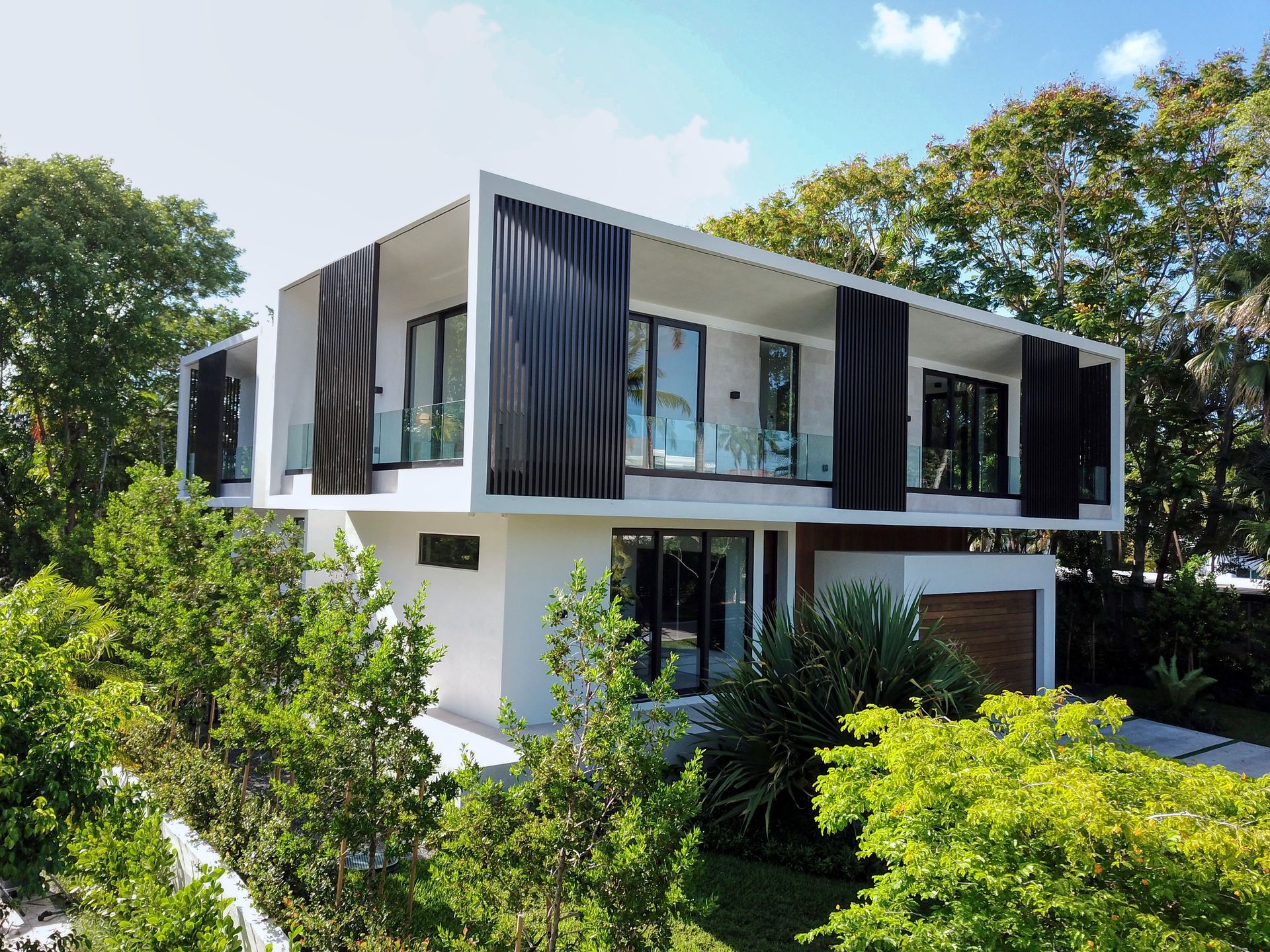 A modern house with a lot of windows is surrounded by trees