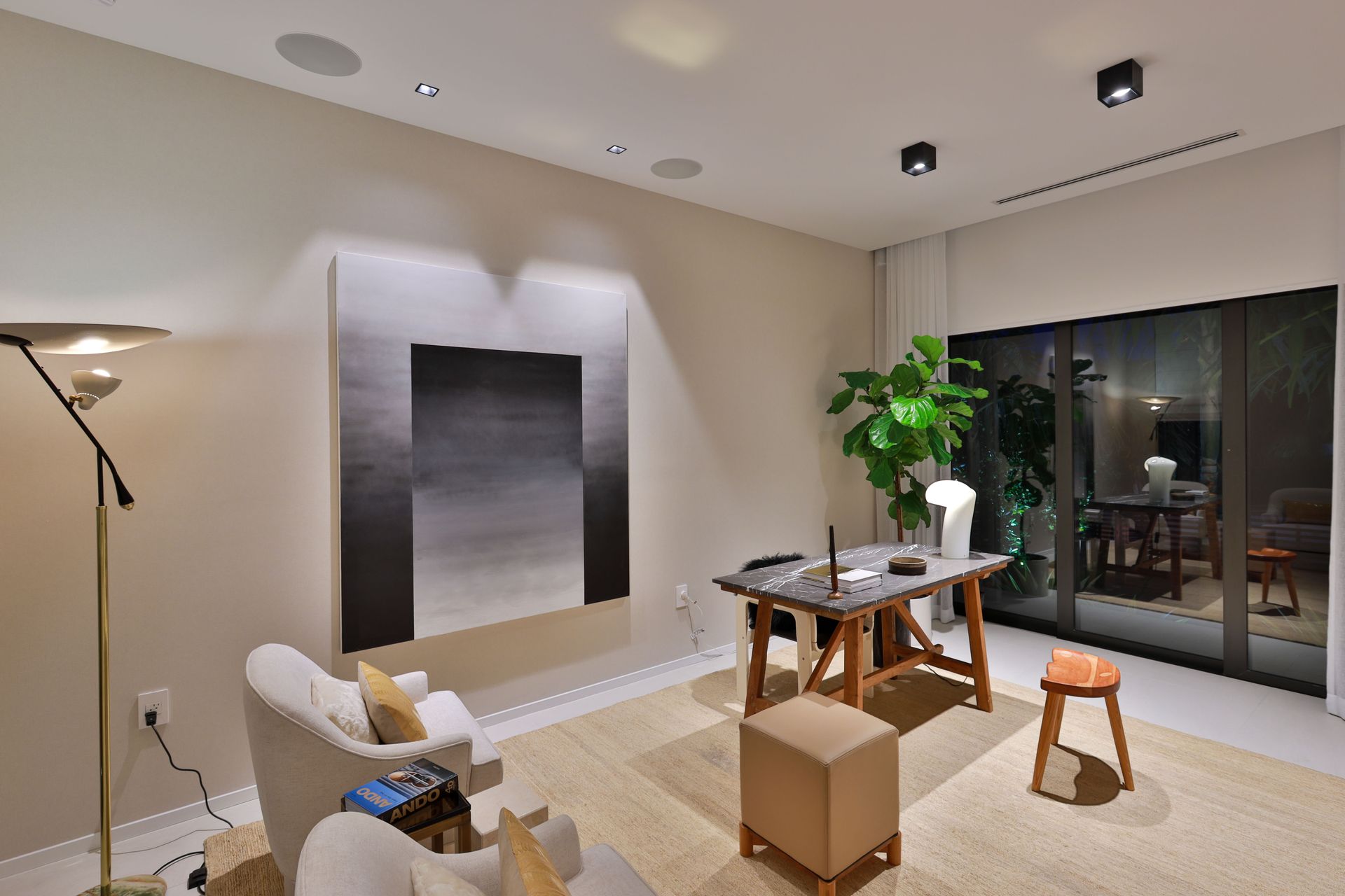 A living room with a desk and chairs and a painting on the wall.