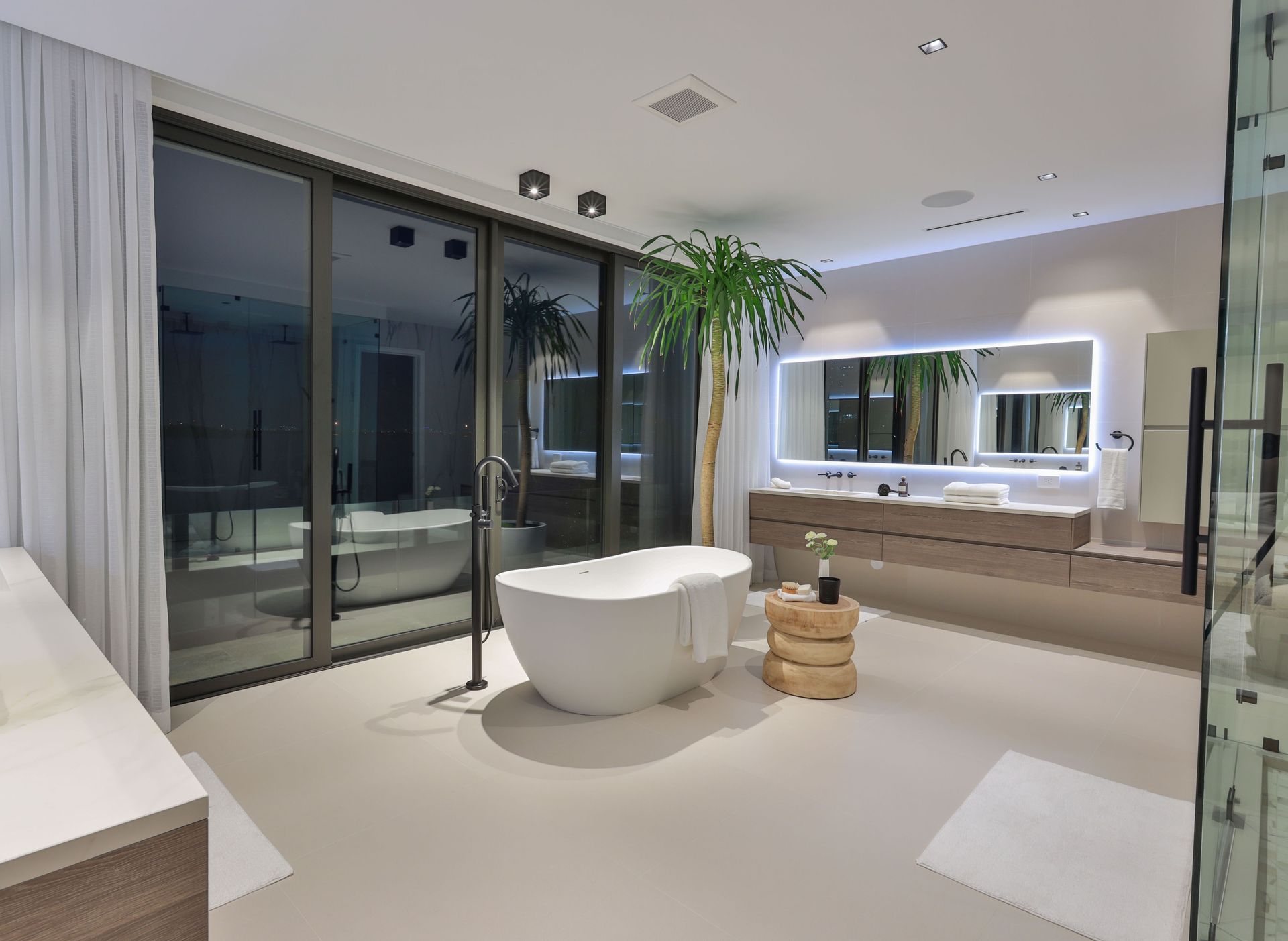 A bathroom with a tub , sink , mirror and sliding glass doors.