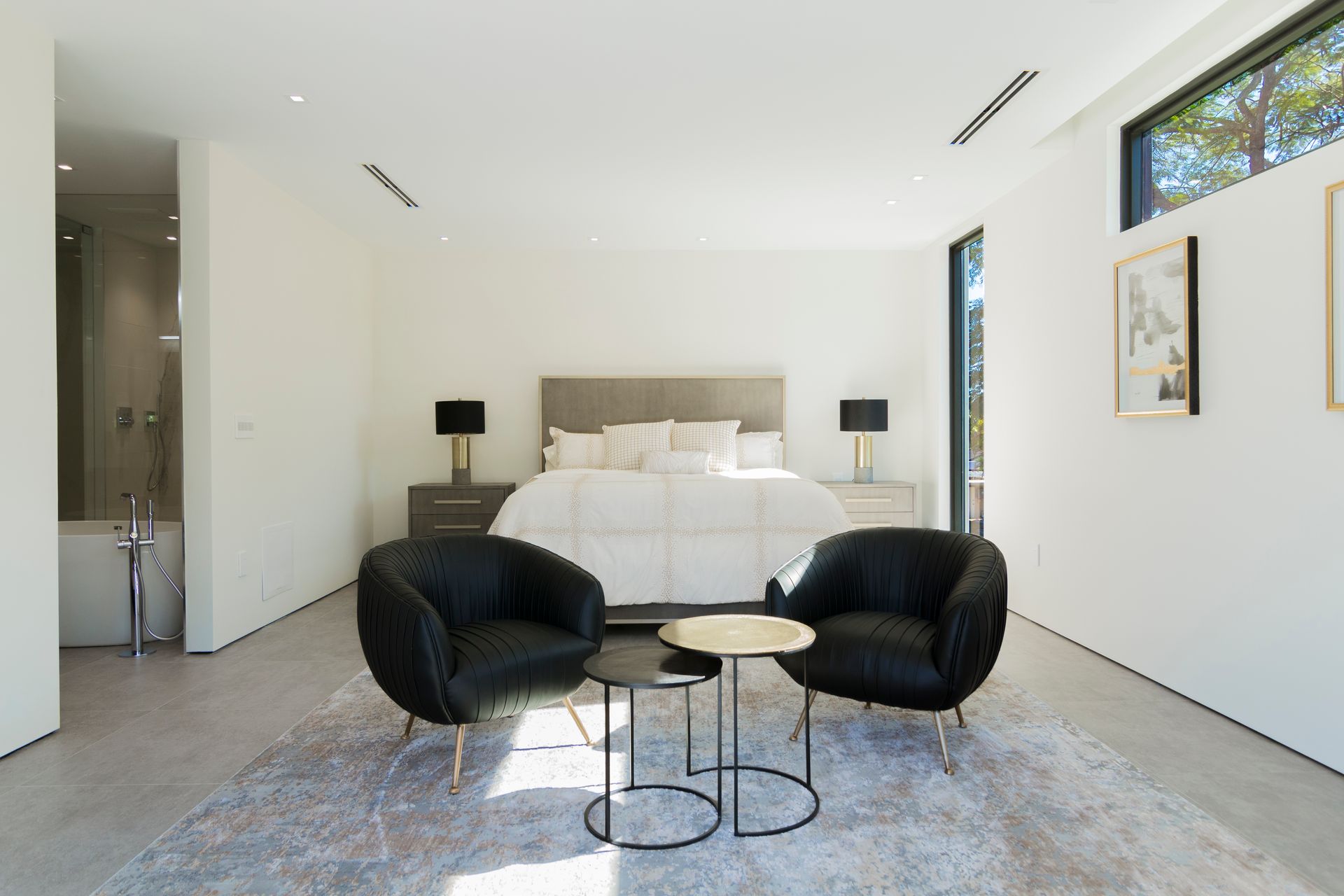 A bedroom with a bed , two chairs , a table and a rug.