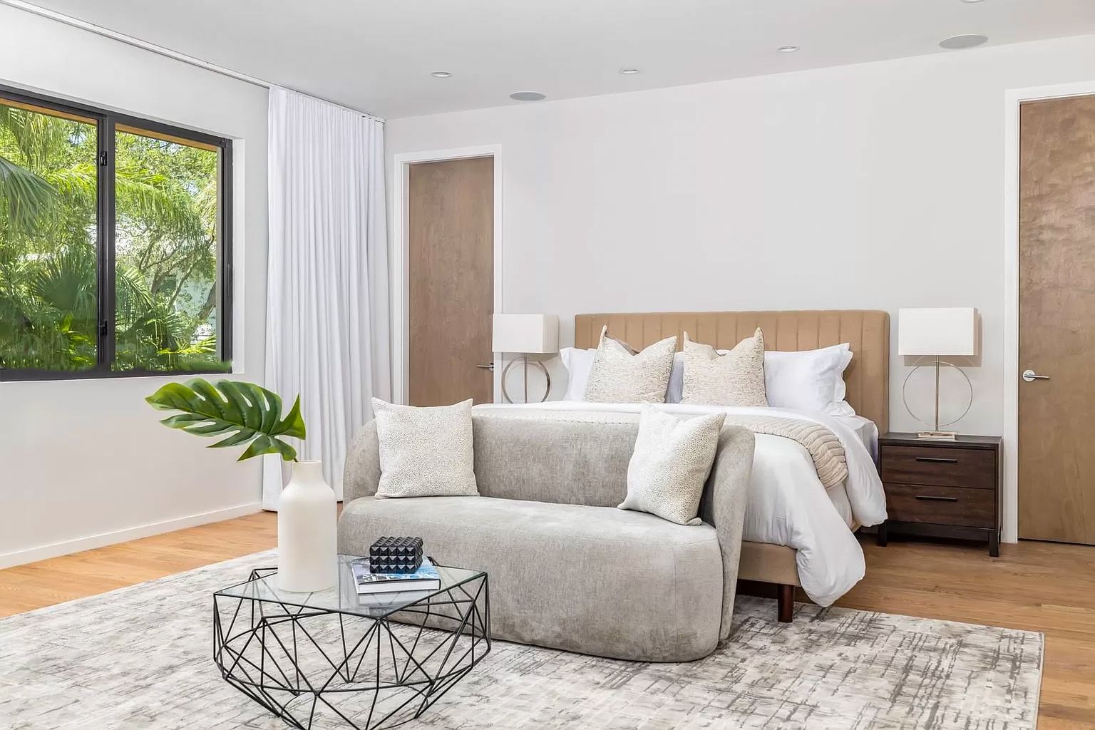 Bedroom with bed, sofa, rug, side tables, window, and modern decor.