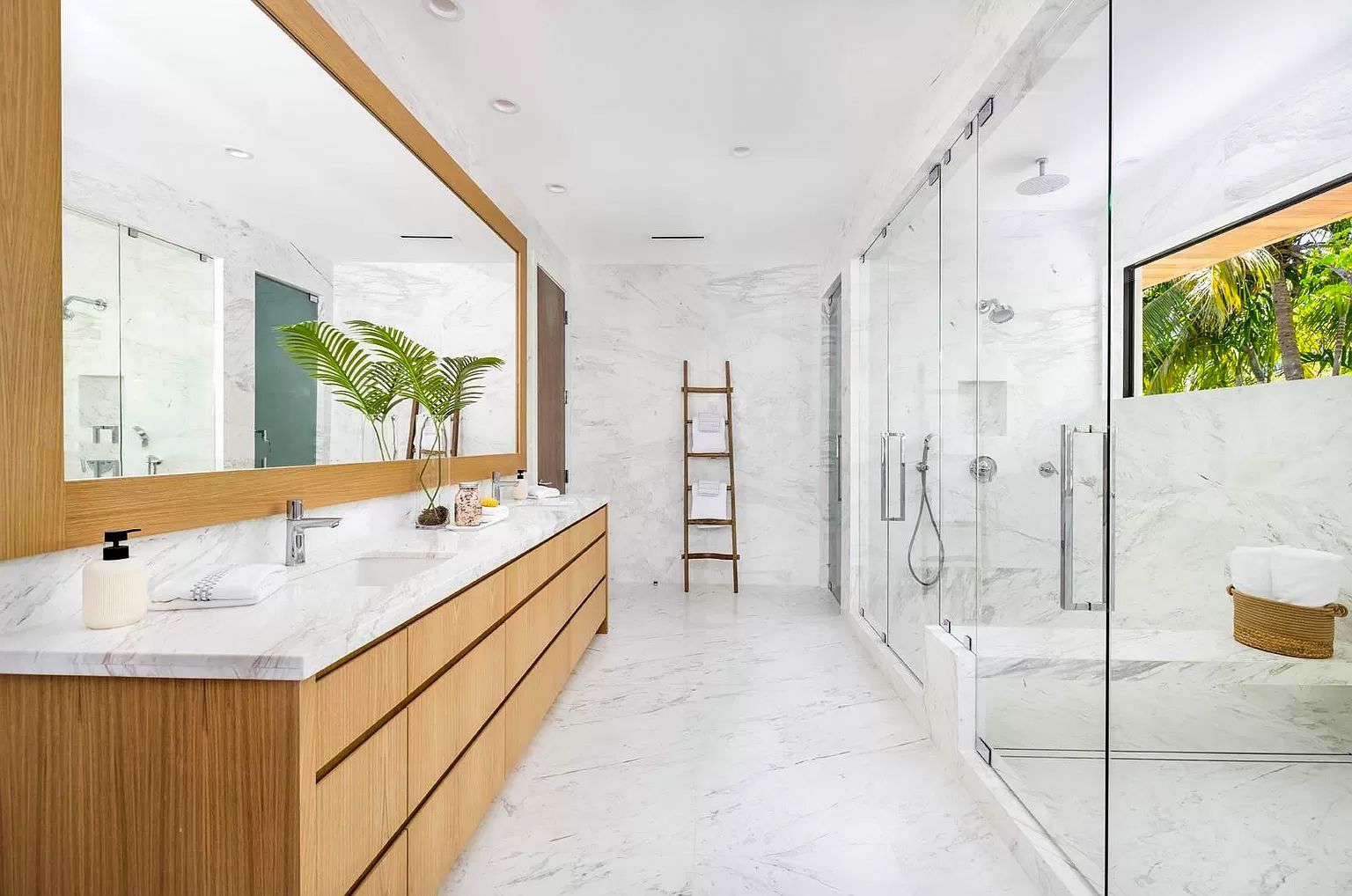 Spacious, modern bathroom with marble and wood accents, glass shower, and large mirror.