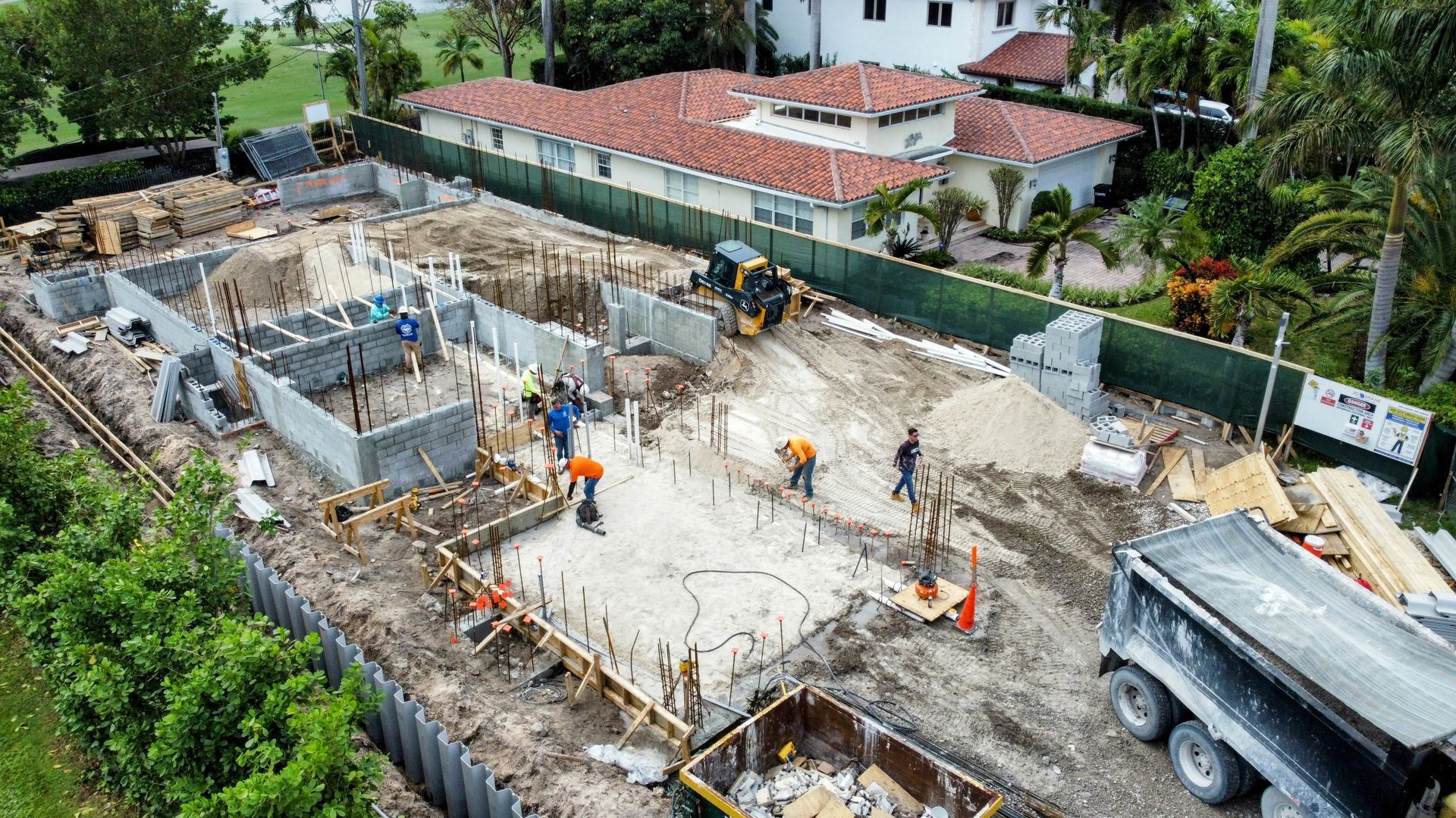 An aerial view of a construction site with a house in the background.