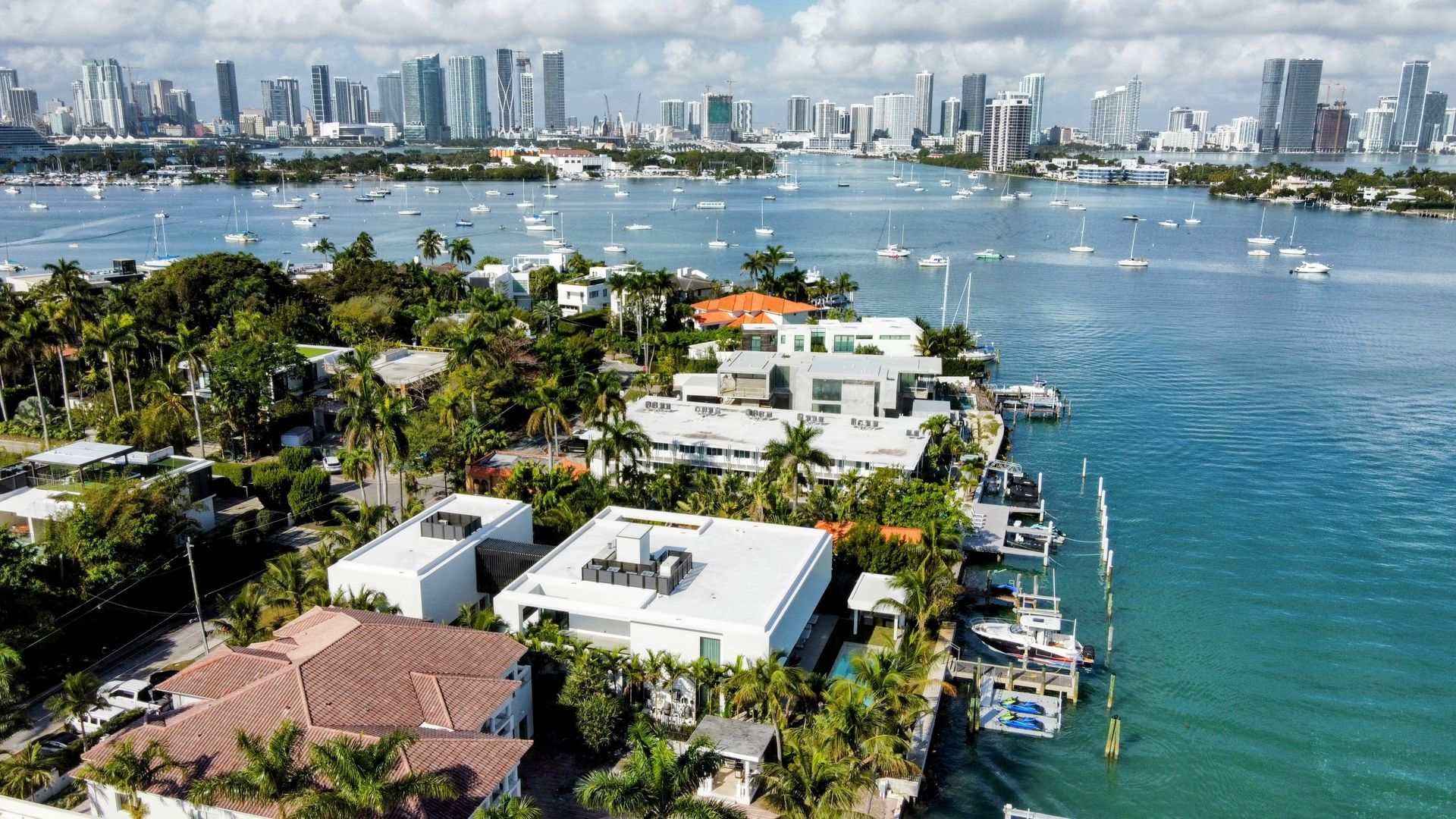 An aerial view of a residential area next to a body of water with a city skyline in the background.