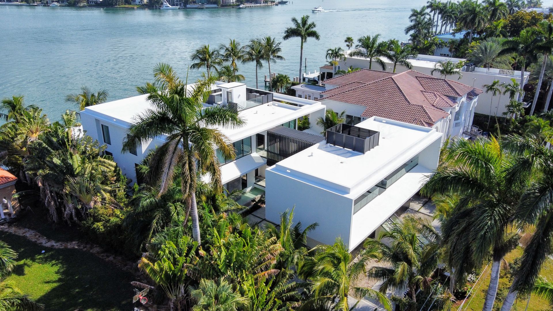 An aerial view of a large white house surrounded by palm trees