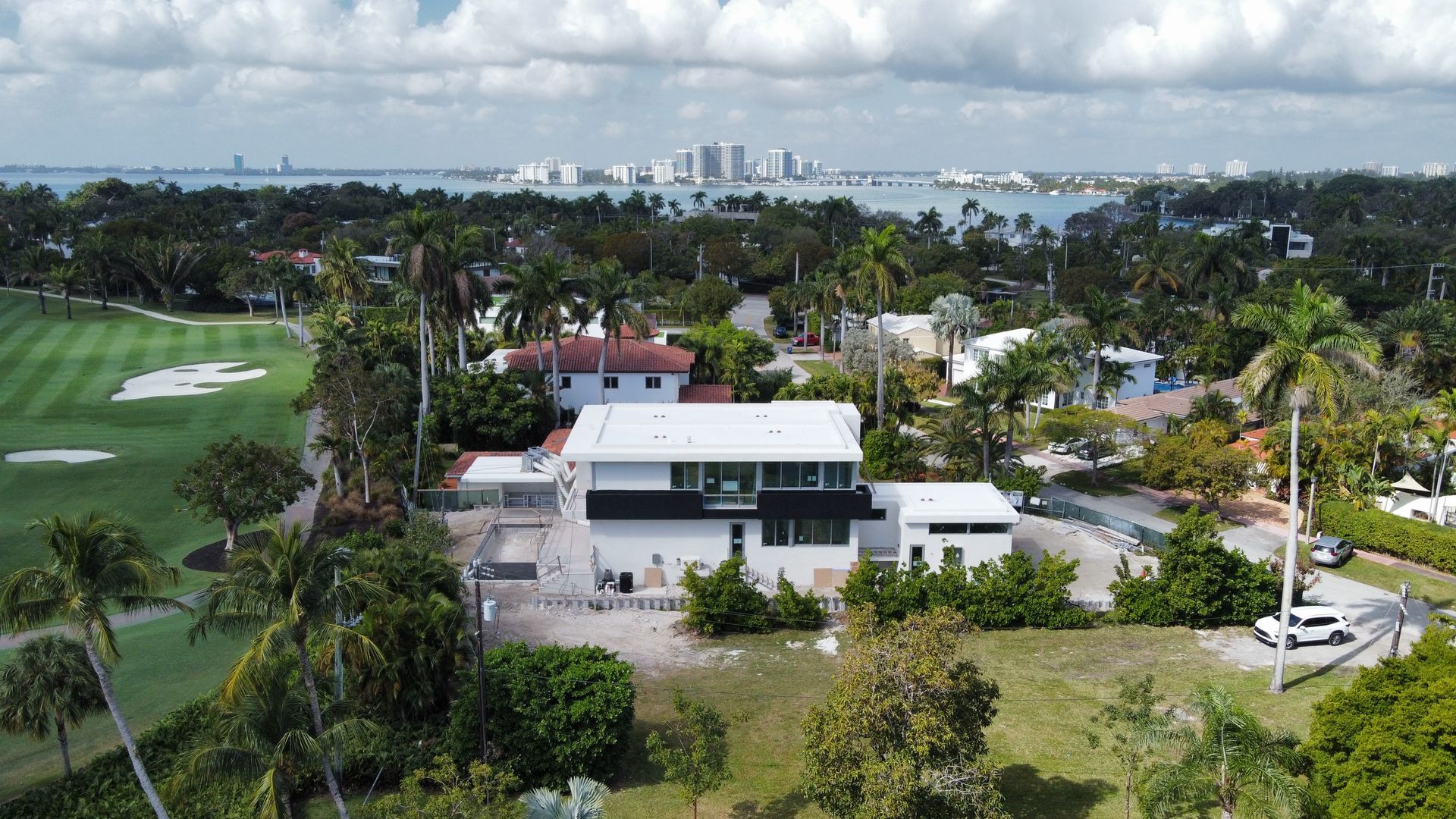 An aerial view of a house surrounded by trees and a golf course.