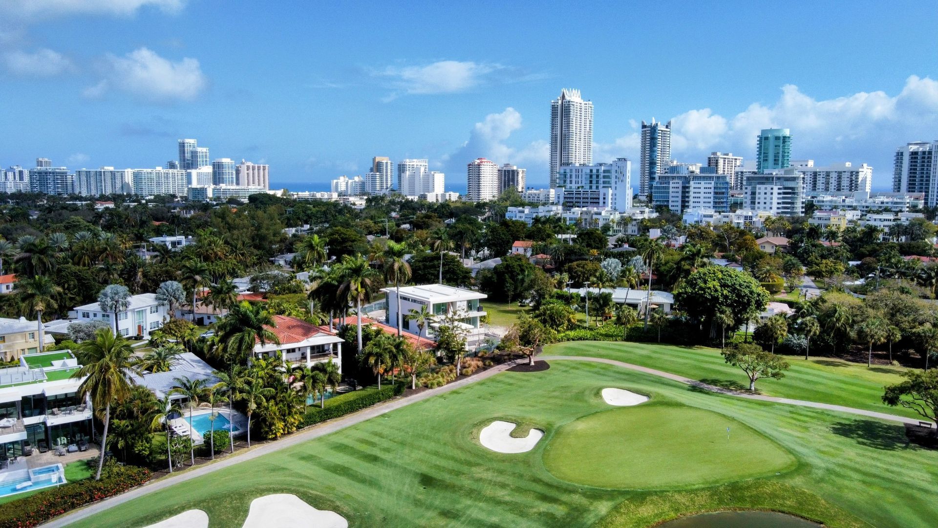 An aerial view of a golf course with a city in the background.