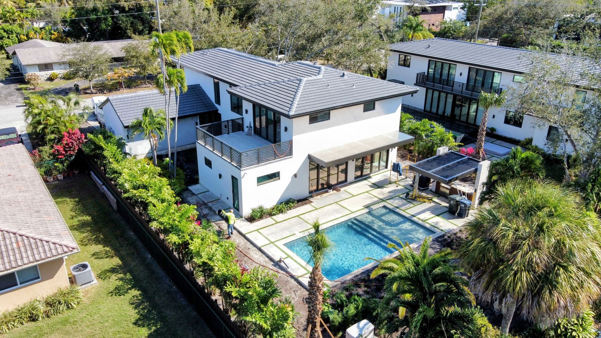 Modern white house with a pool in a yard surrounded by green landscaping.