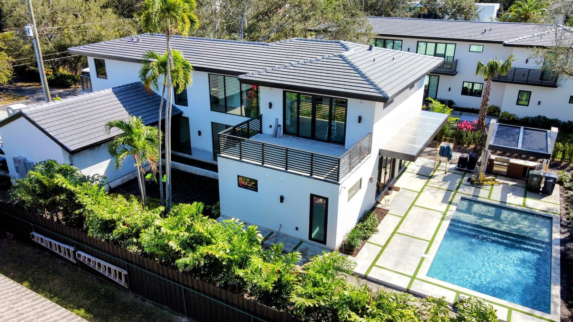 White modern house with a pool and tile roof.