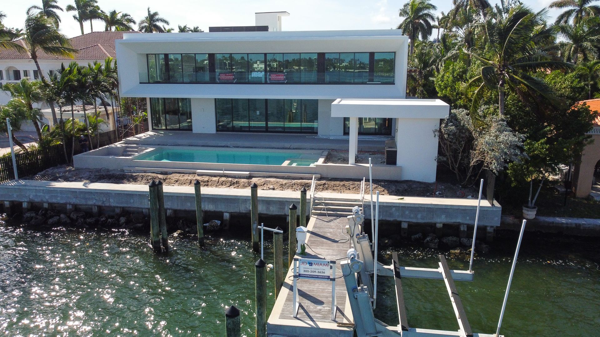 A large white house with a pool and a dock in front of it