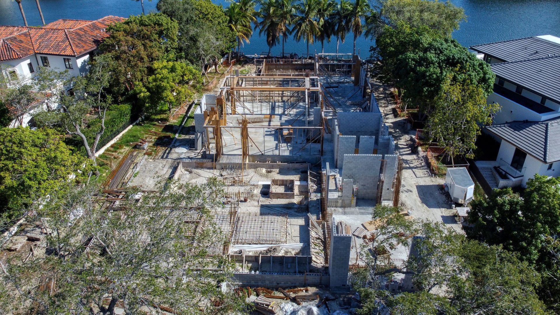 Construction site of a home with exposed framing, viewed from above, near water.