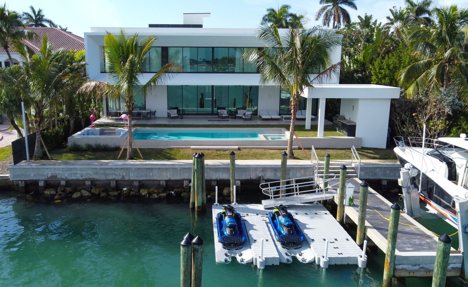 Two jet skis are docked in front of a large house