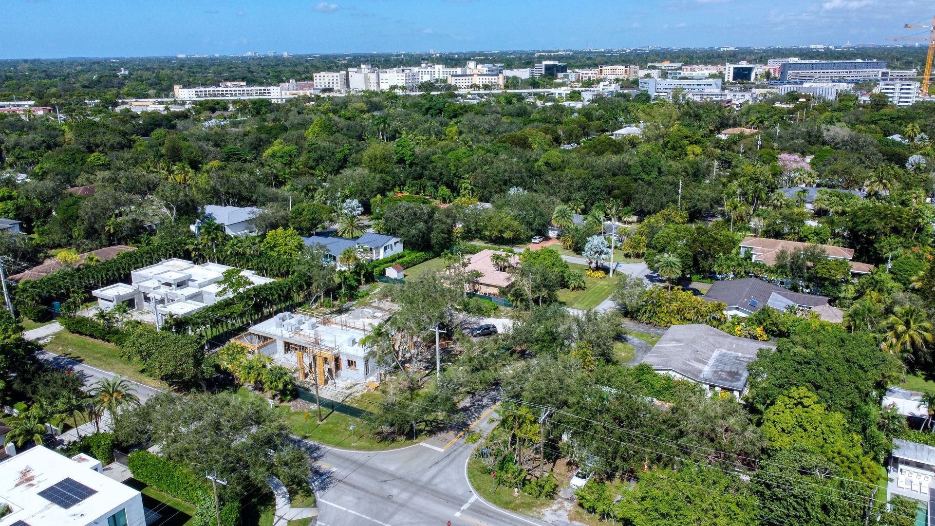 Aerial view of a suburban neighborhood with trees, houses, and roads on a sunny day.
