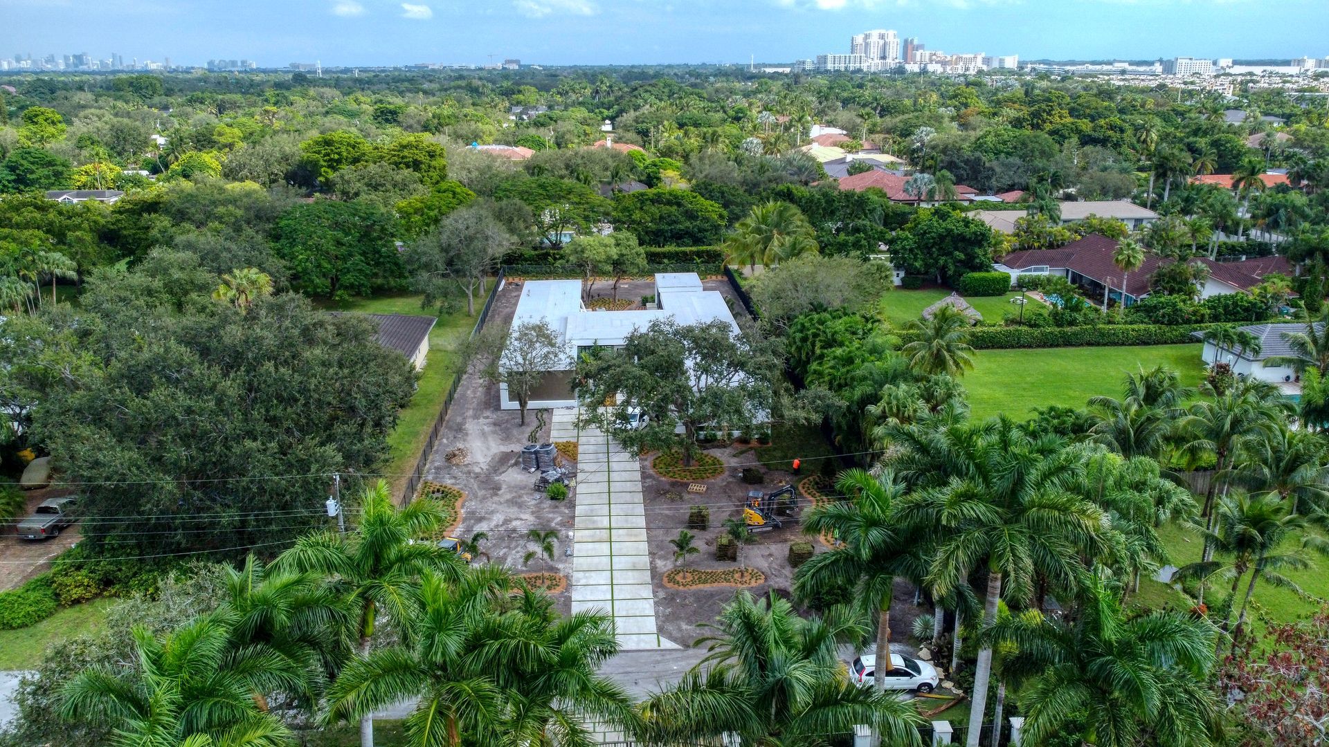 Aerial view of a construction site amid lush greenery, showcasing concrete foundation and cleared land.