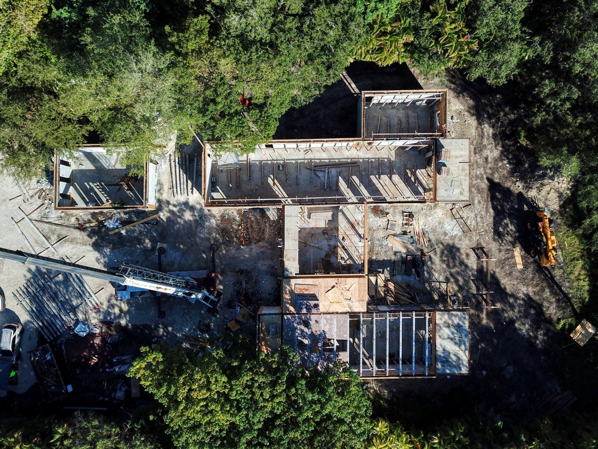 Aerial view of a building's framing, surrounded by trees and construction debris.