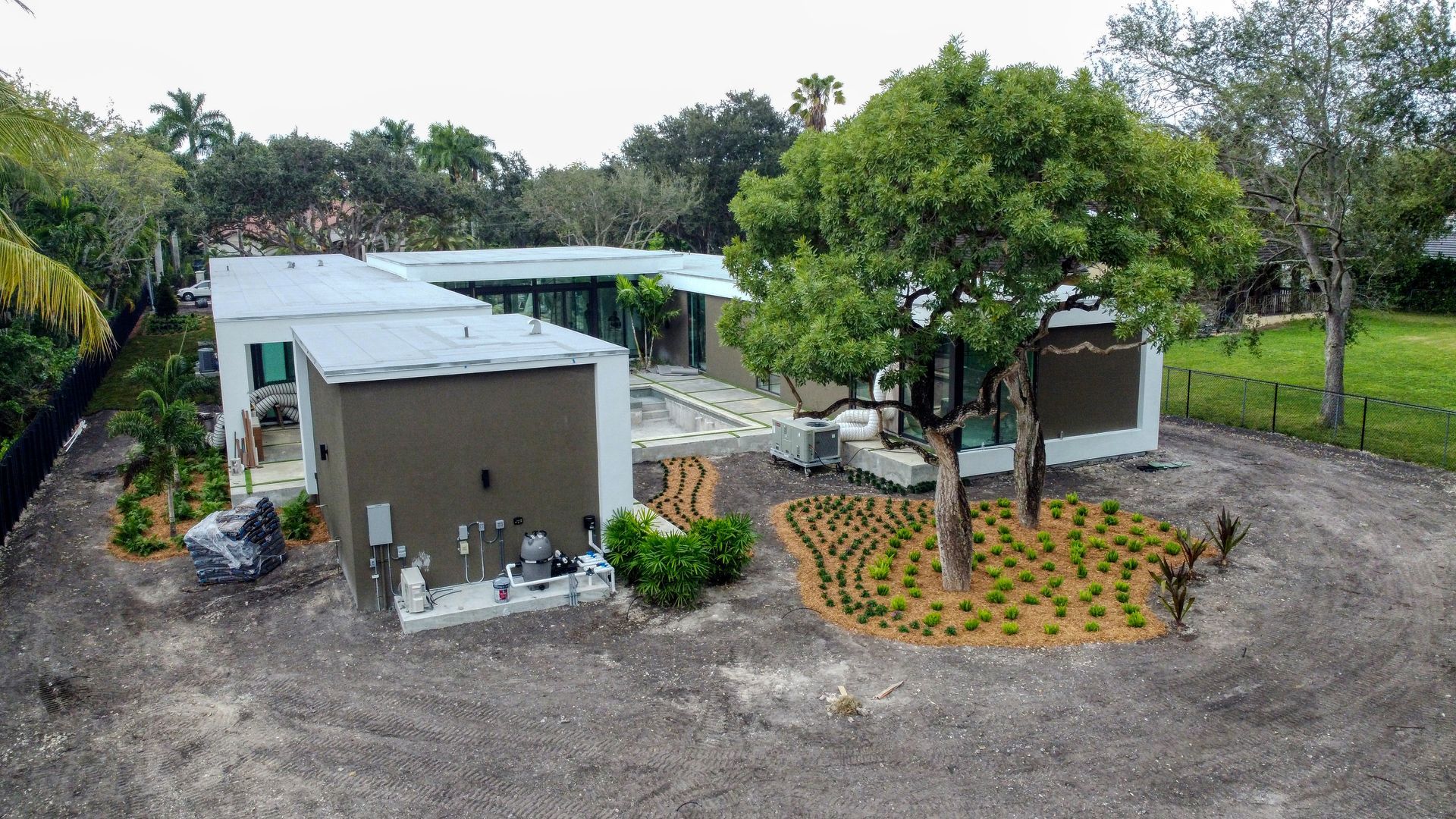 Modern, flat-roofed house with a large tree in the yard. Exterior is primarily gray and white.