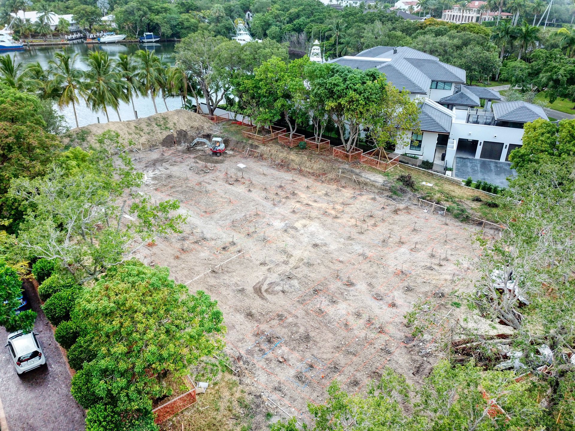 Cleared lot with construction equipment; luxury homes in background.