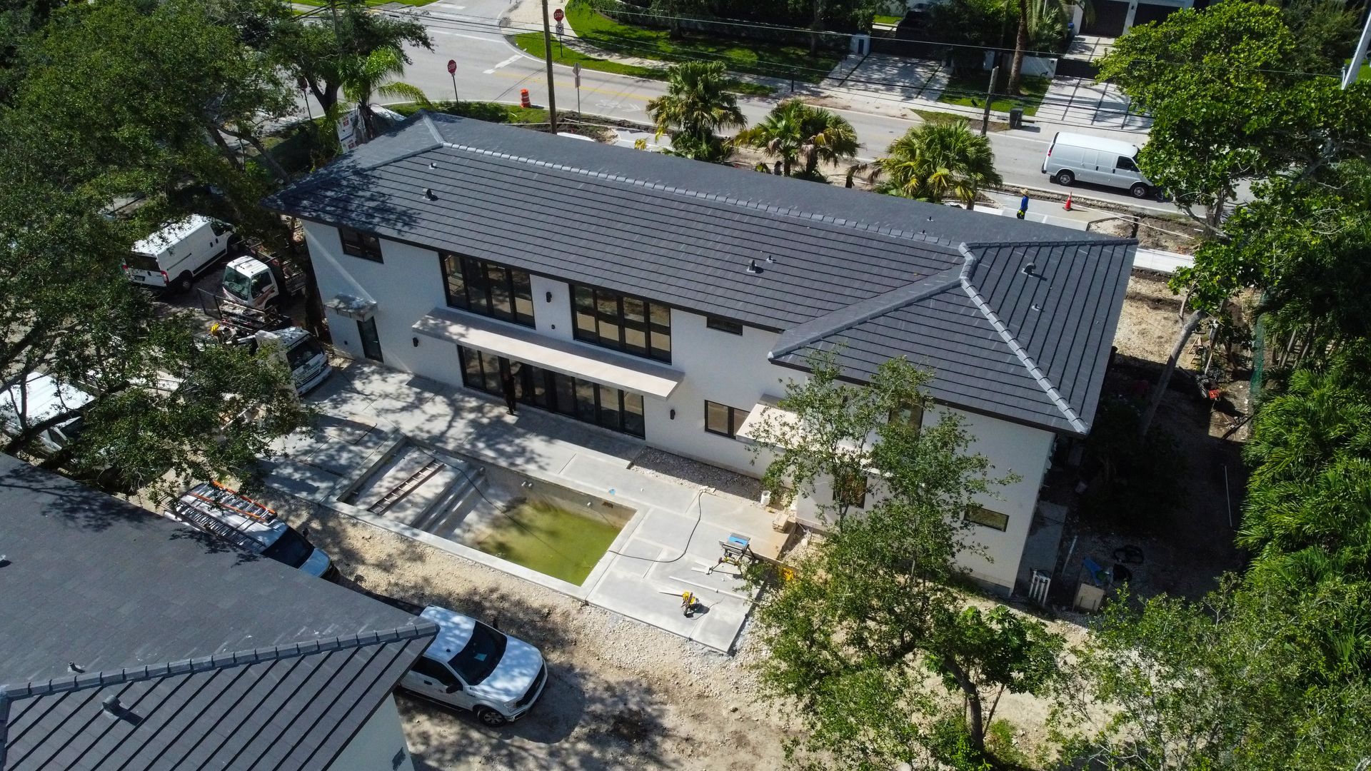 Aerial view of a two-story white house with a dark gray roof, next to a smaller building with a similar roof.
