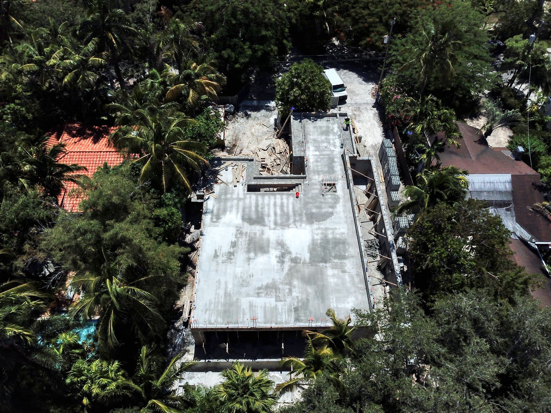 Aerial view of a gray concrete roof surrounded by lush green trees, possibly a building under construction.