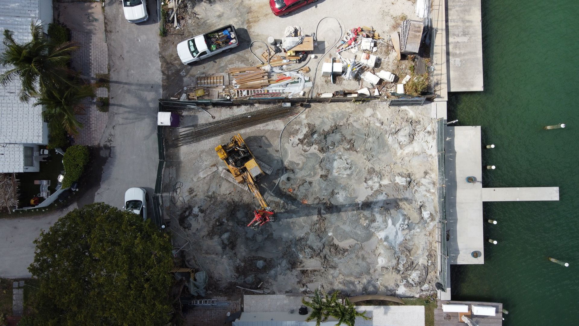 Aerial view of a construction site next to water, a bulldozer works among debris.