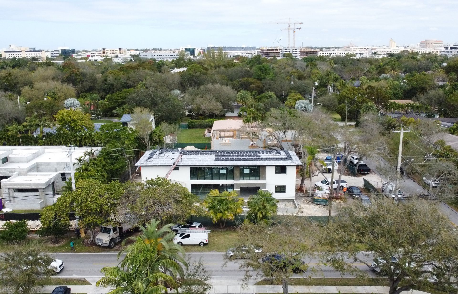 Aerial view of a two-story building under construction surrounded by trees and vehicles.