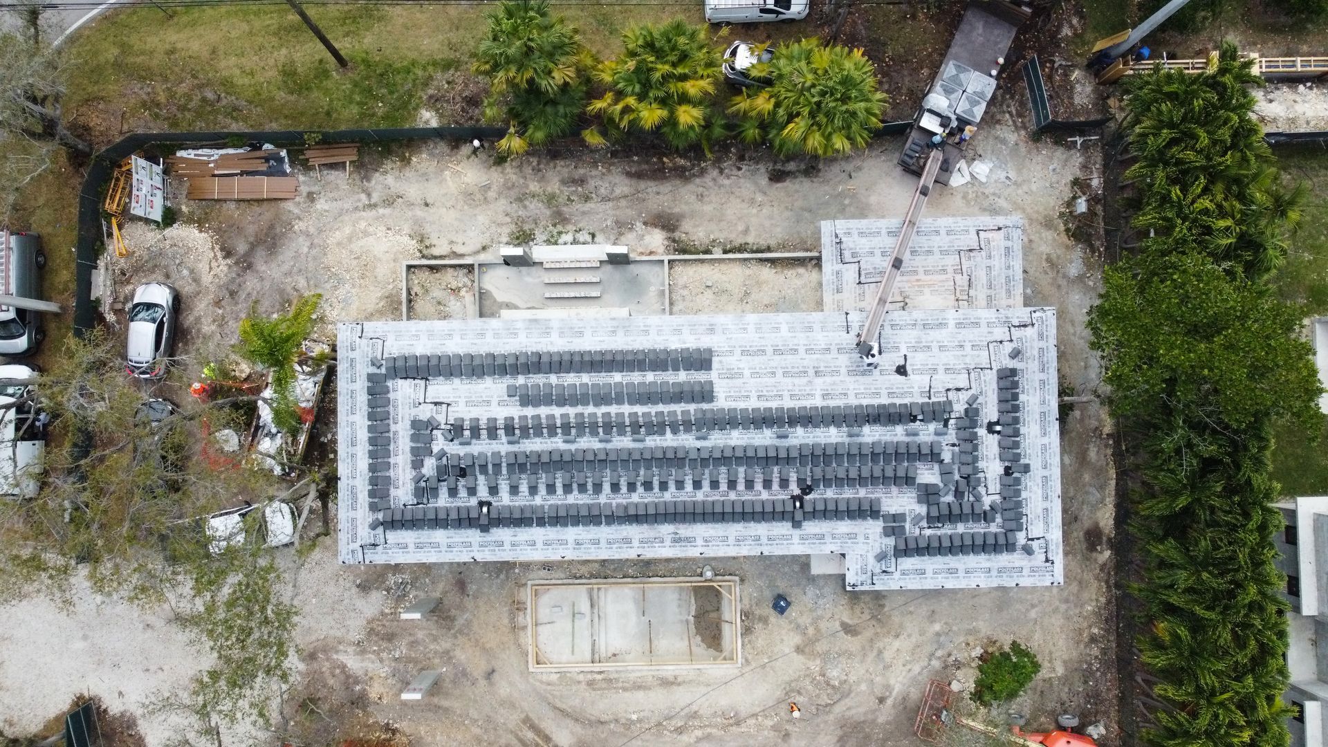 Overhead view of a building under construction, showing a concrete foundation and framework. Construction debris surrounds.