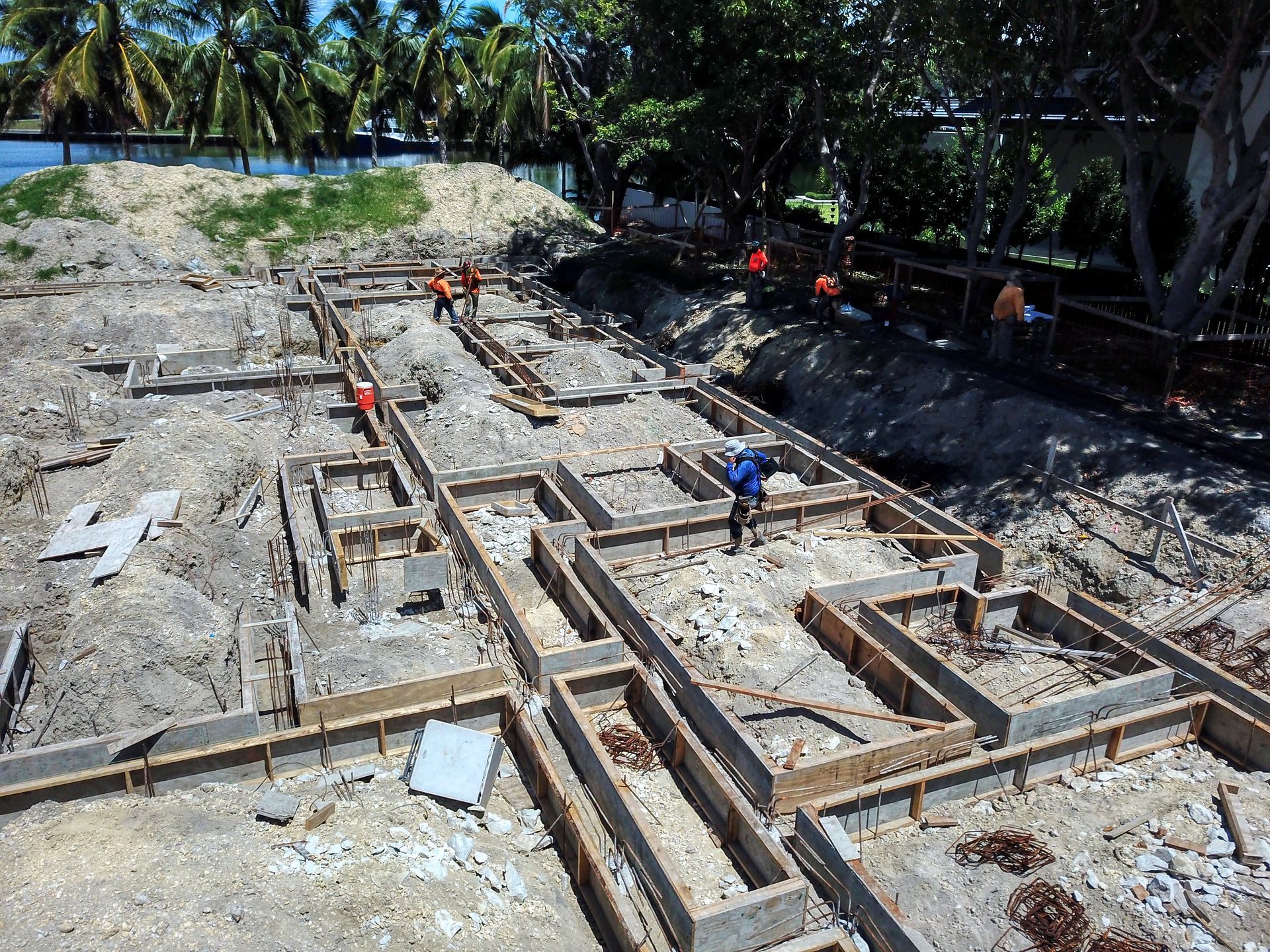Construction site, workers building foundation. Wooden forms frame trenches. Sunlight.