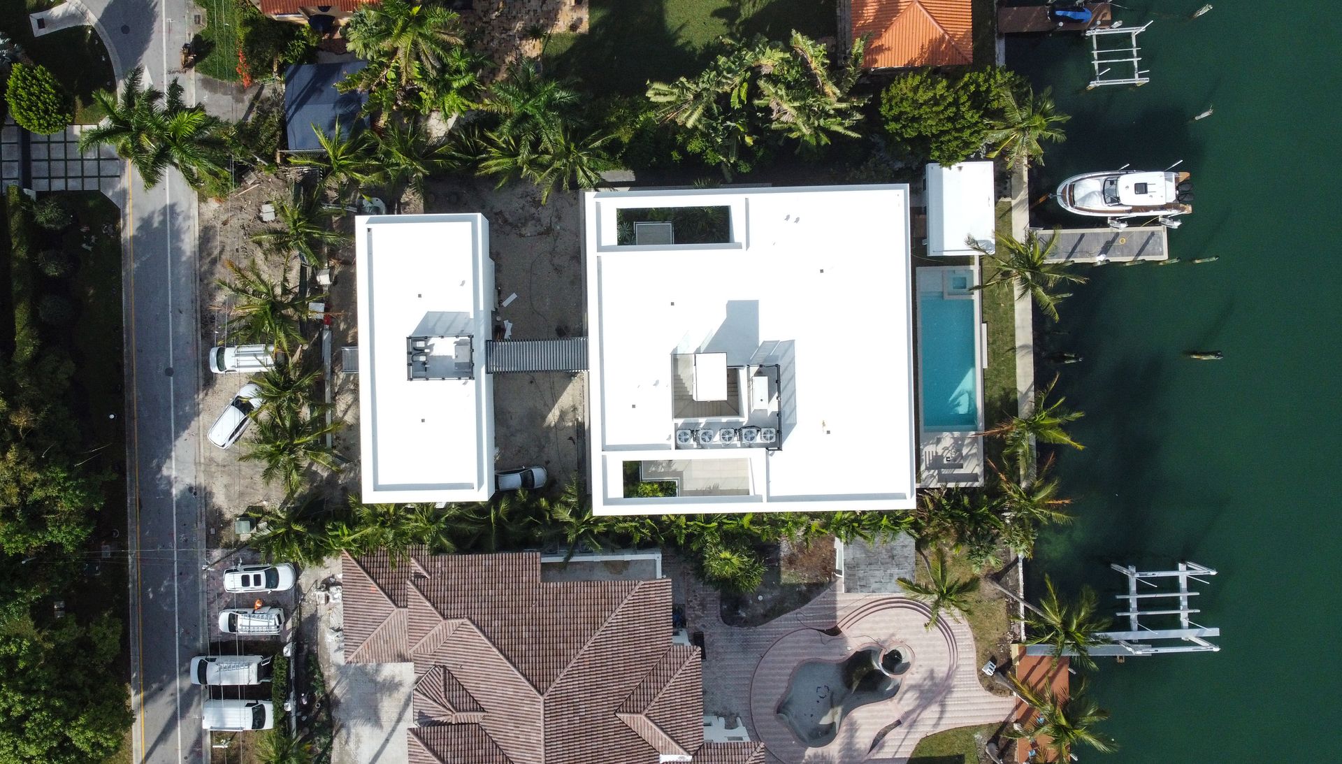 An aerial view of a house with a pool and boats in the water