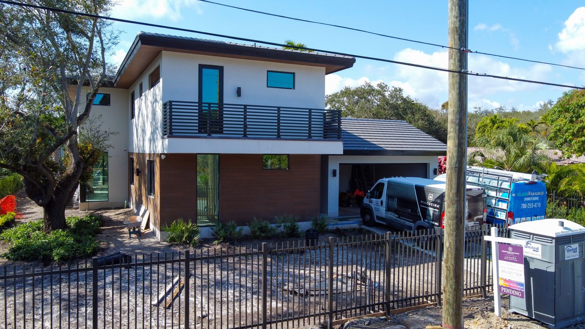 Modern two-story house with a garage and black iron fence. A van is parked in the driveway.