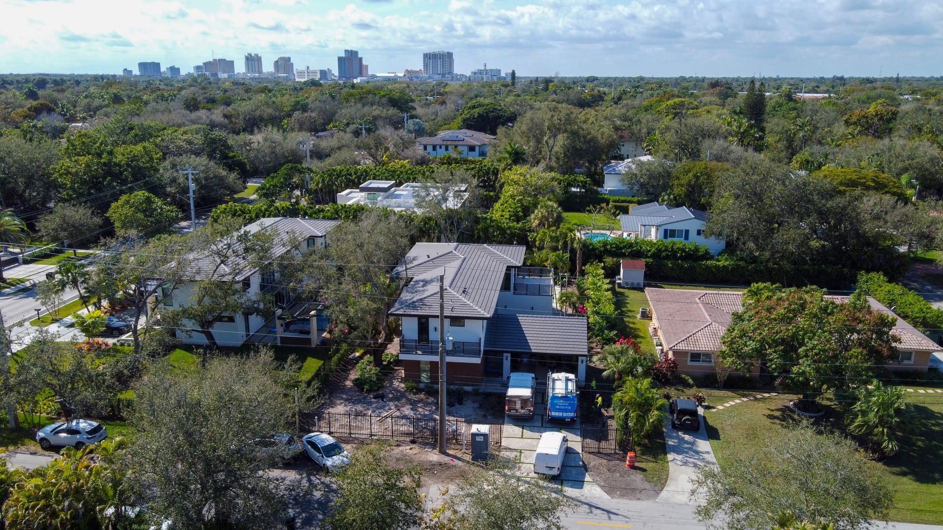 Aerial view of houses with a city skyline in the background. Construction in progress on one home.