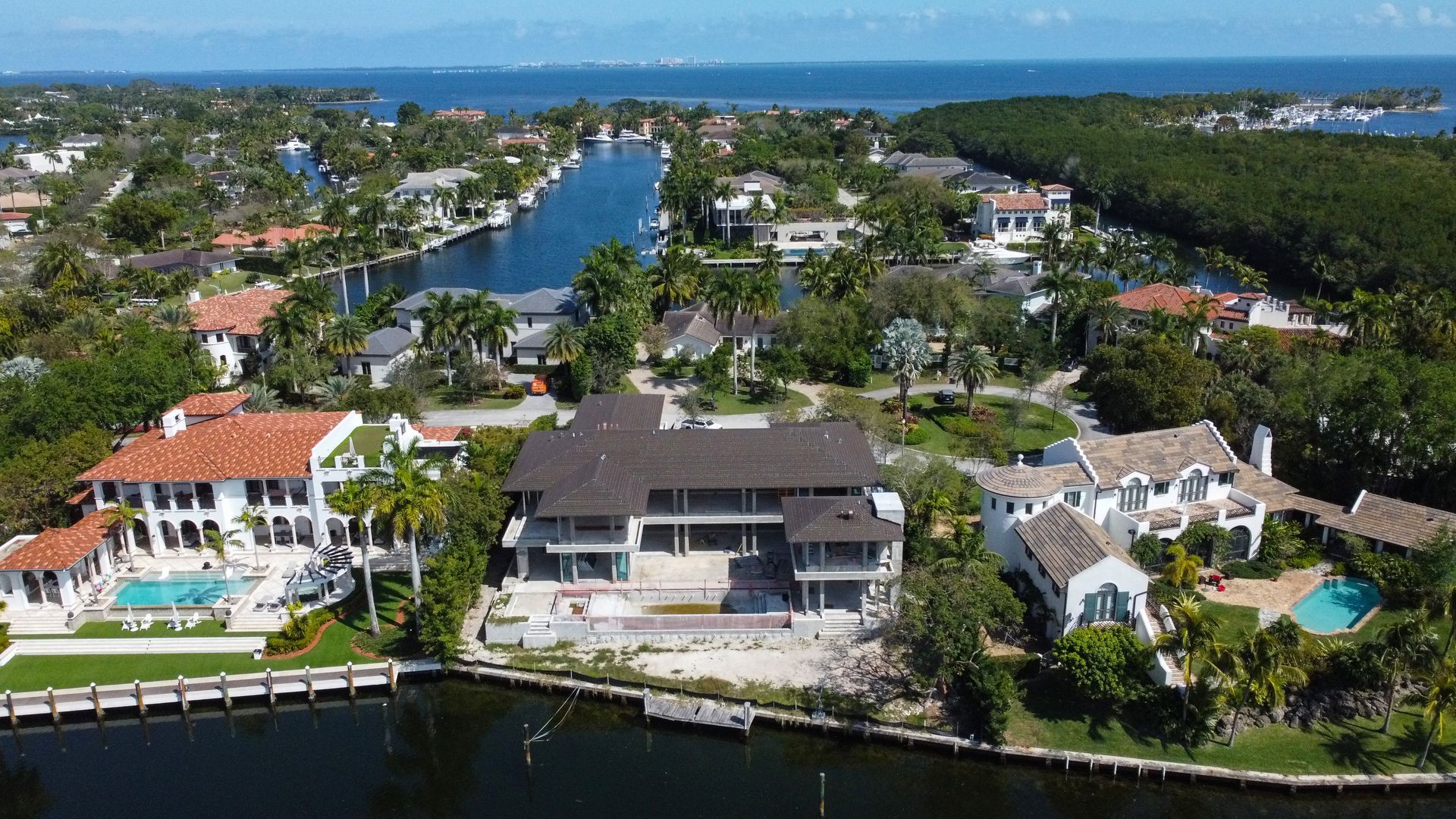 Aerial view of luxury waterfront homes with canals and ocean in background.